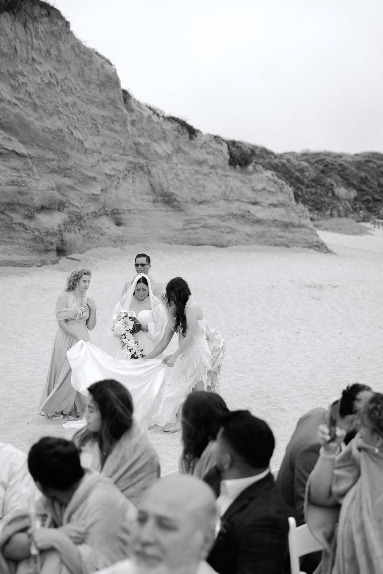 A sequence of black and white photos showing a crowd gathering on a beach with cliffs in the background.