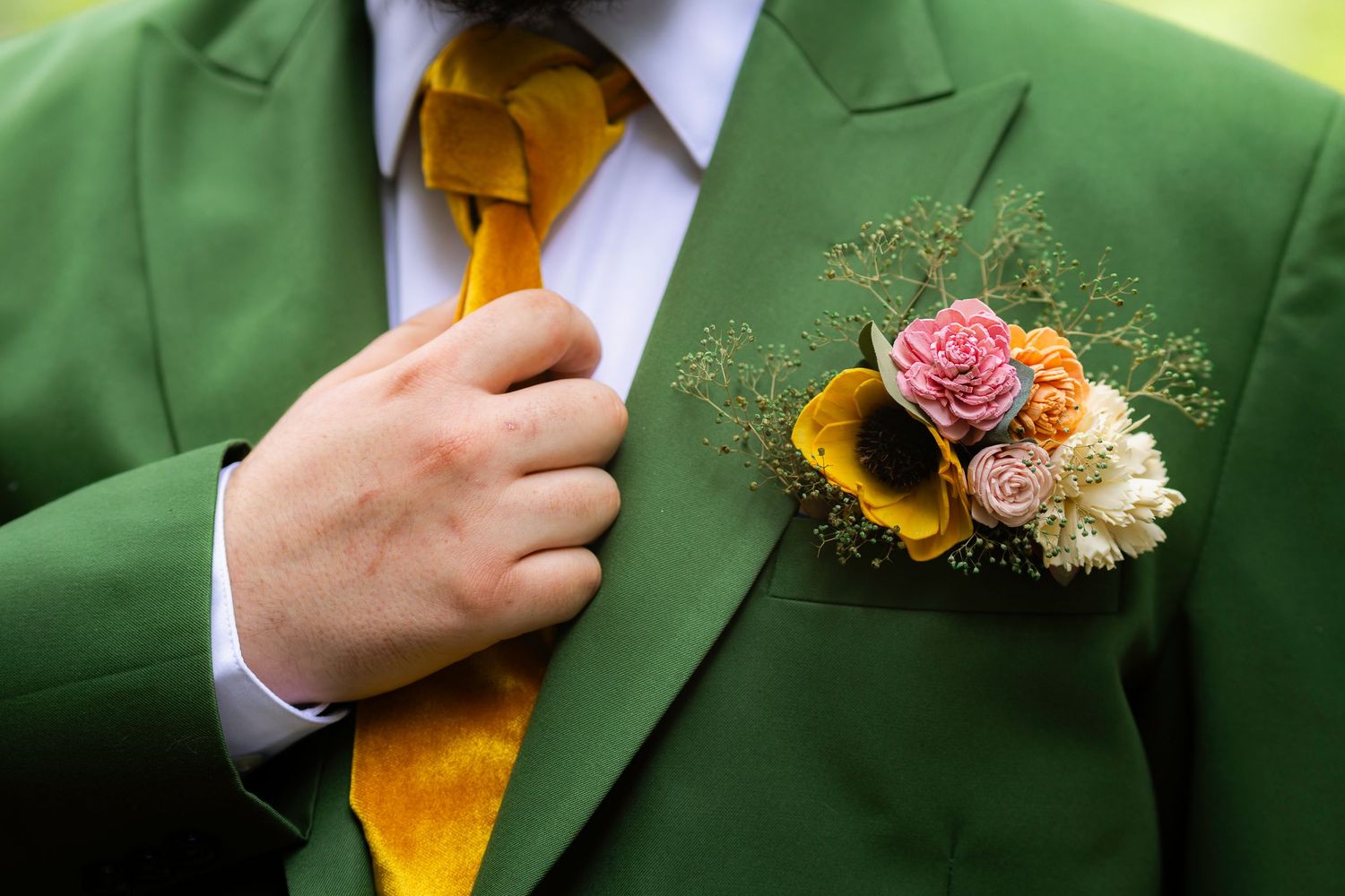 Close-up of yellow and pink floral boutonniere pinned to bright green suit jacket lapel.