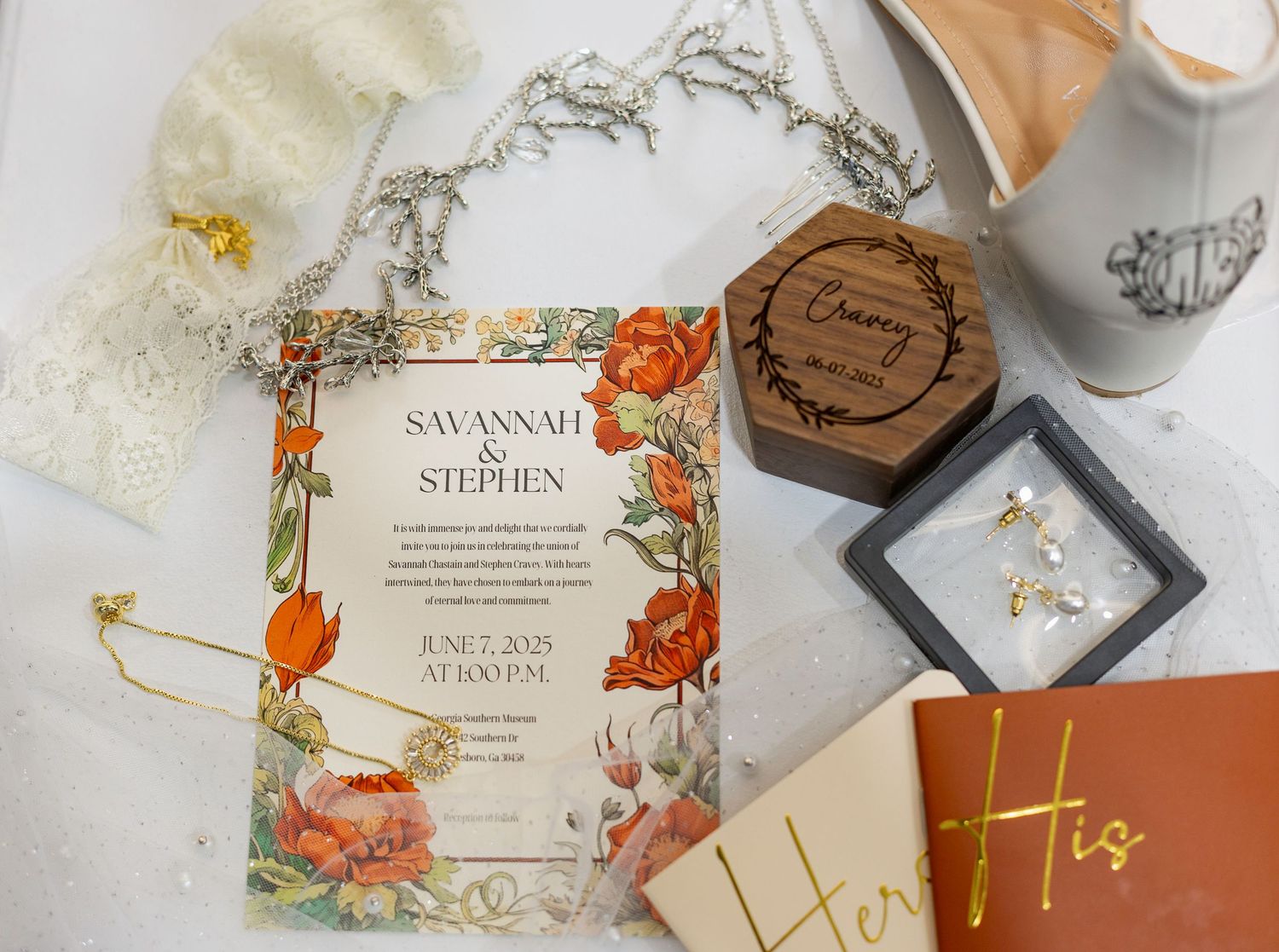 Elegant floral wedding invitations and envelopes with gold accents and wooden details laid out on white surface.