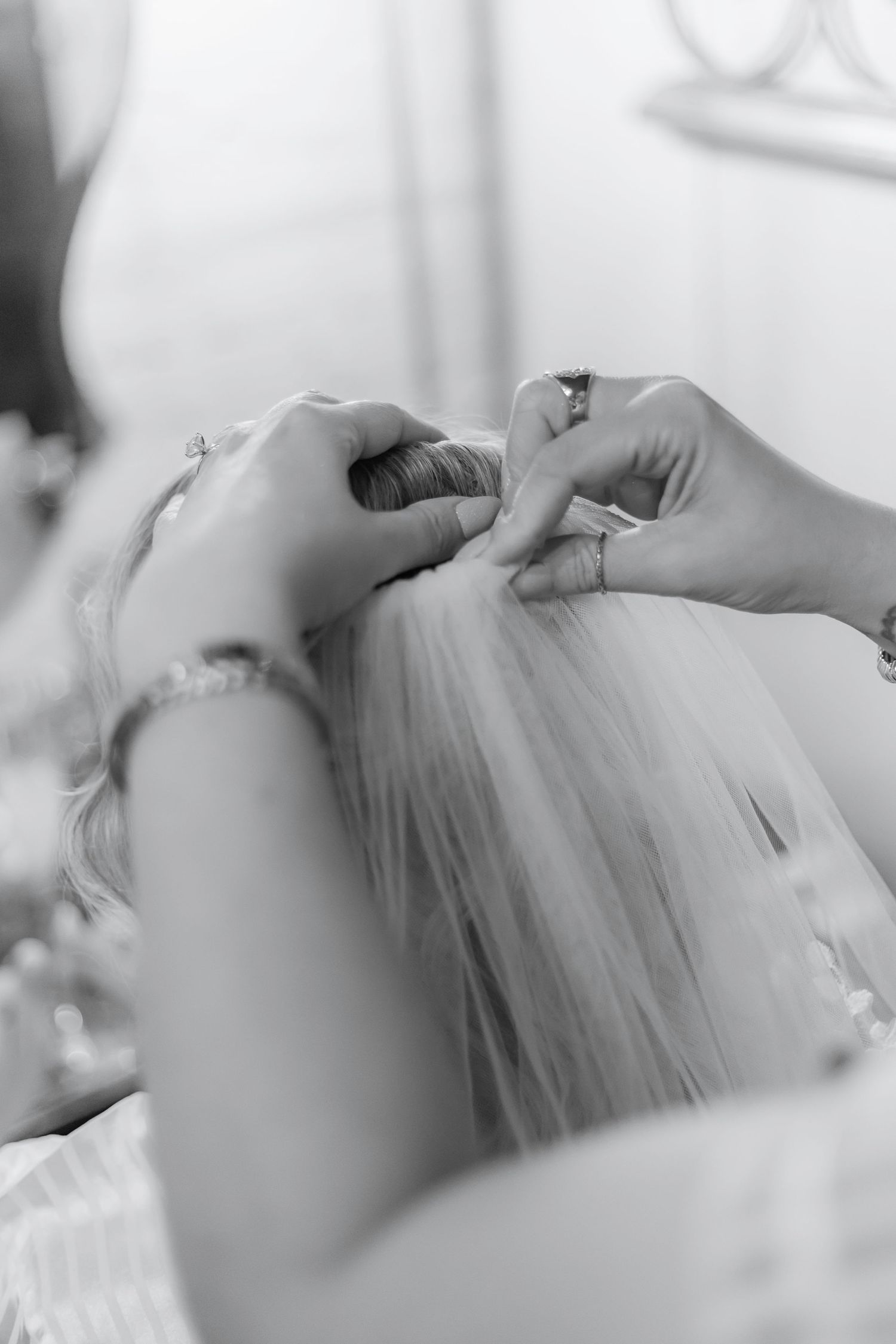 Close-up of hands adjusting a white wedding dress veil.