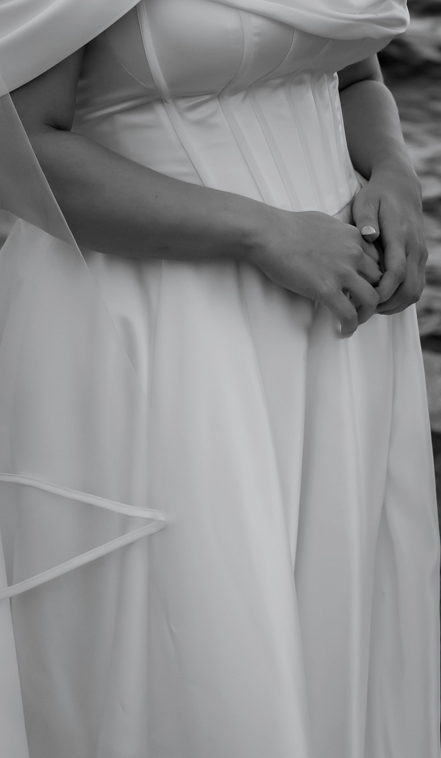Close-up details of white wedding dress fabric showing elegant draping and pleats in a monochromatic style.