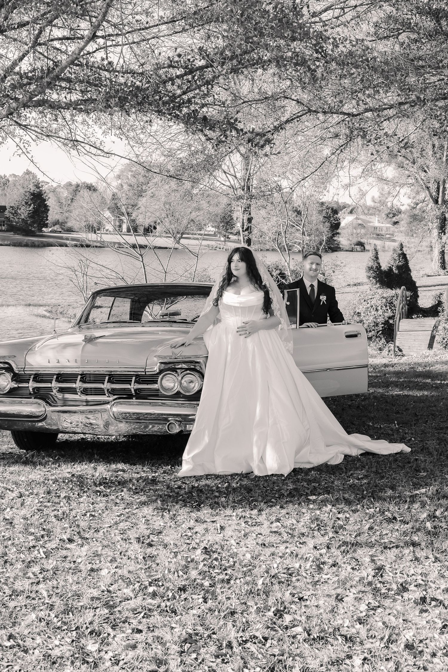 A black and white wedding photo series with a vintage car and couple posing in a natural outdoor setting.