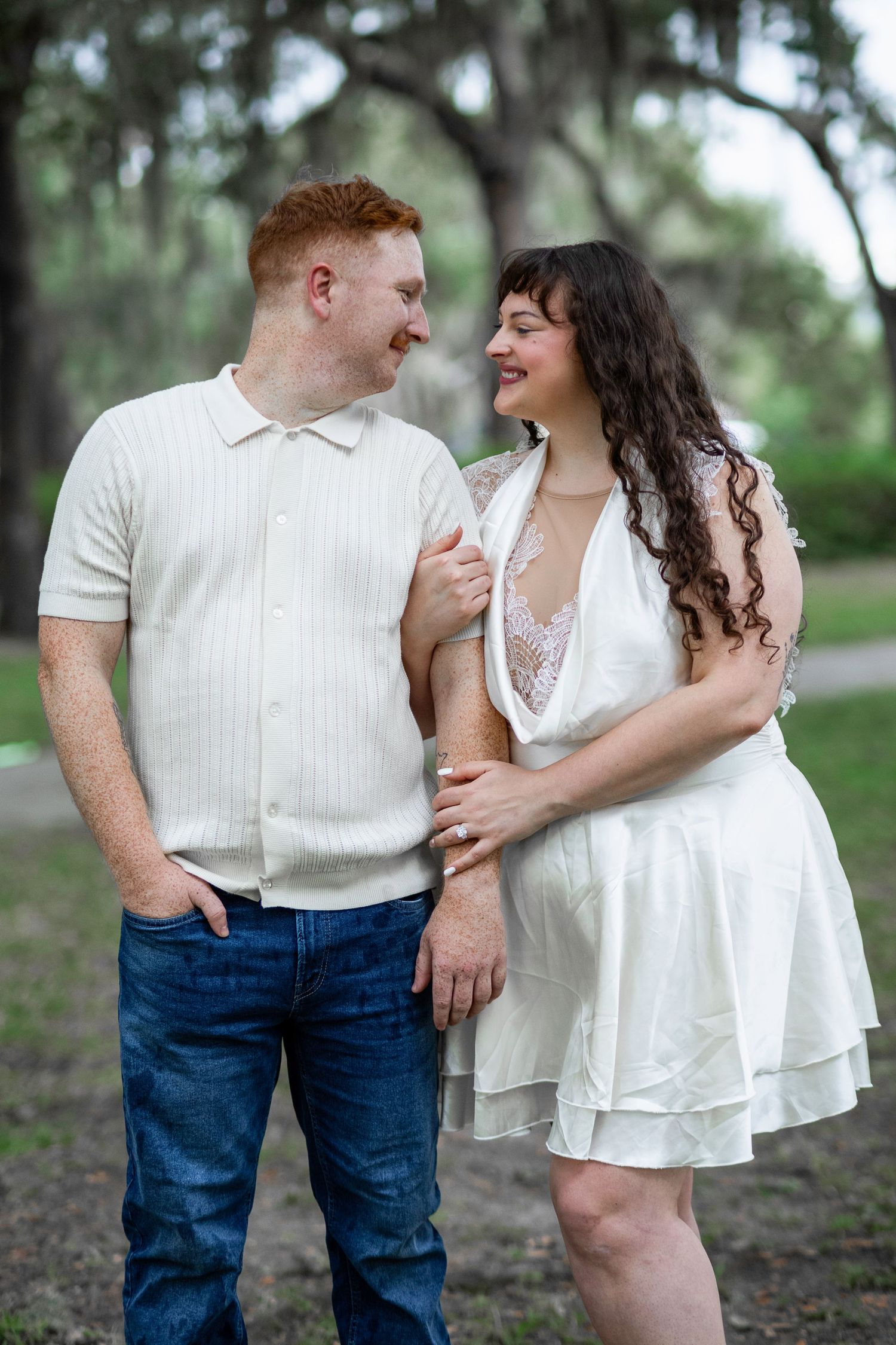 Romantic outdoor couple photography session featuring white and denim outfits under tree canopy.