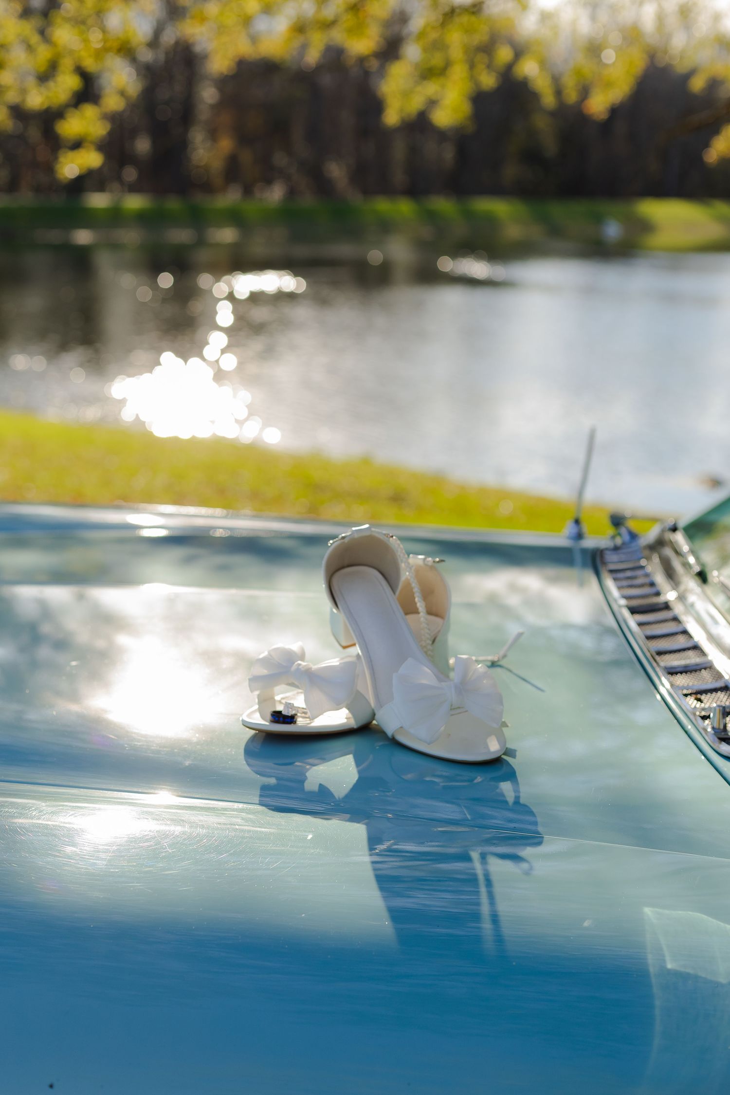 White paper boat floating on reflective blue surface with sunlight and trees in background.