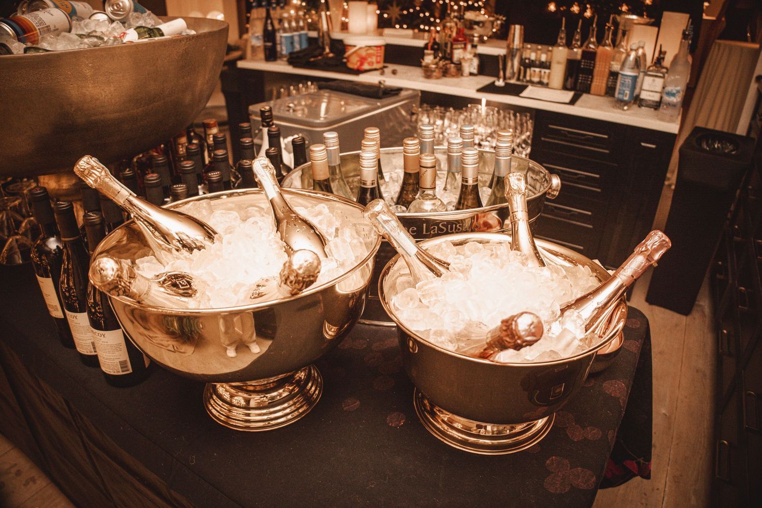 Two large silver champagne buckets filled with ice and bottles at an elegant bar setup.