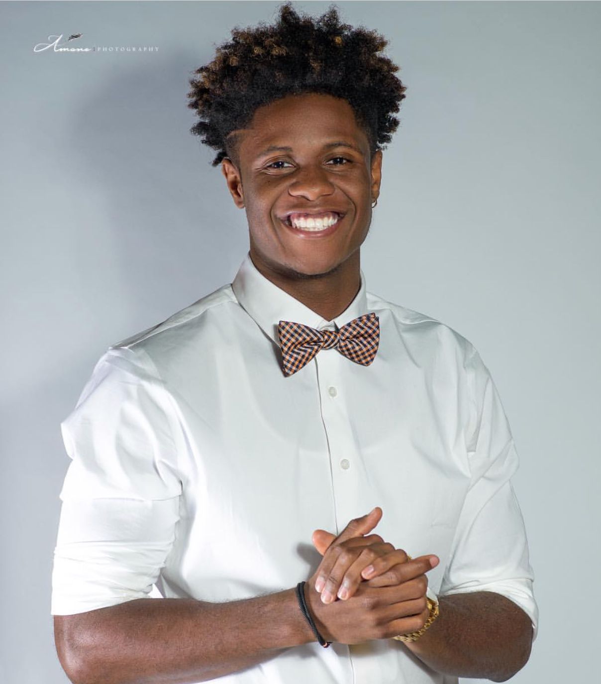 Studio portrait of person wearing bow tie and white shirt with cheerful smile.