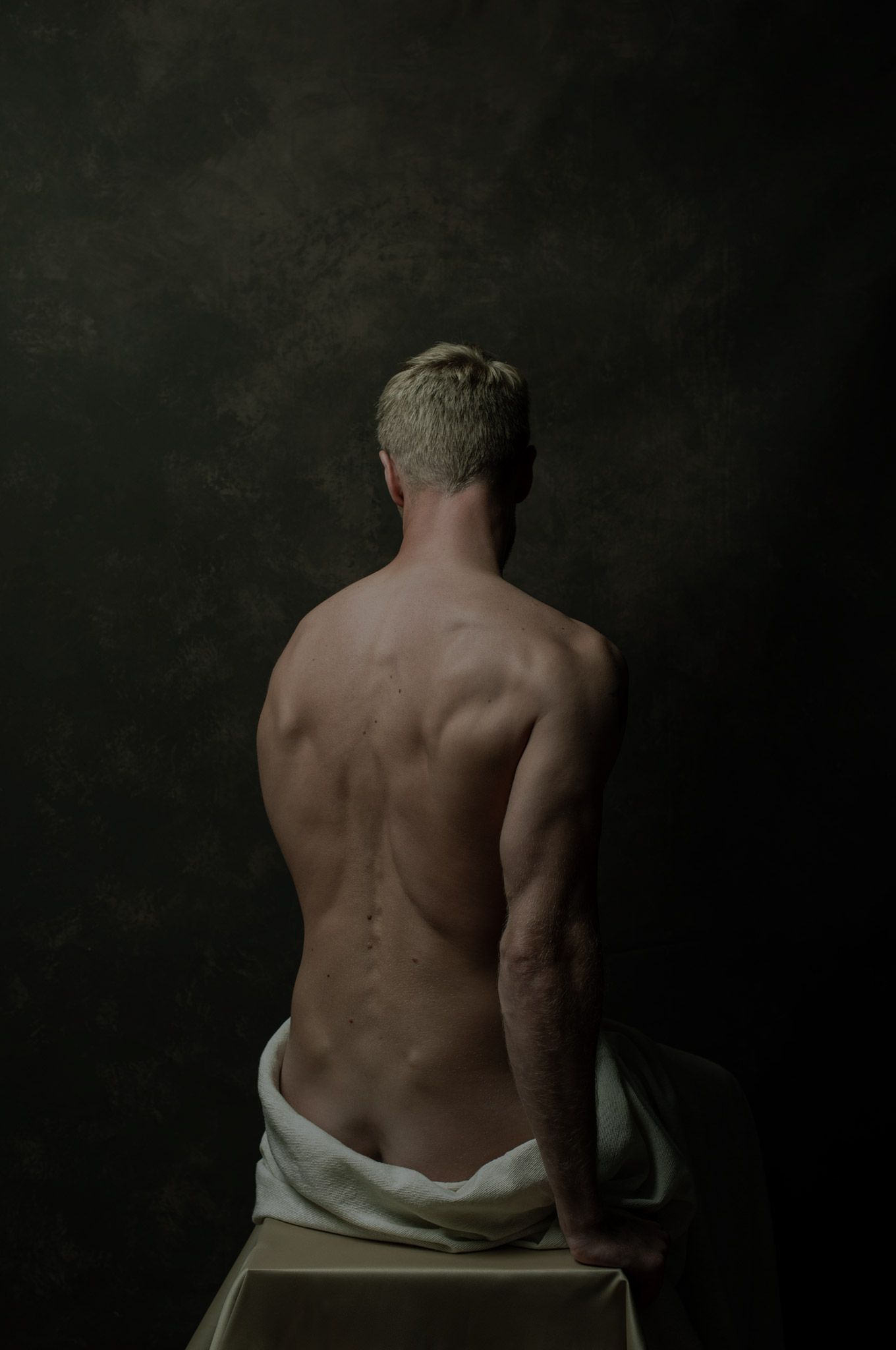 Foto van gespierde man in studio gefotografeerd van achter.