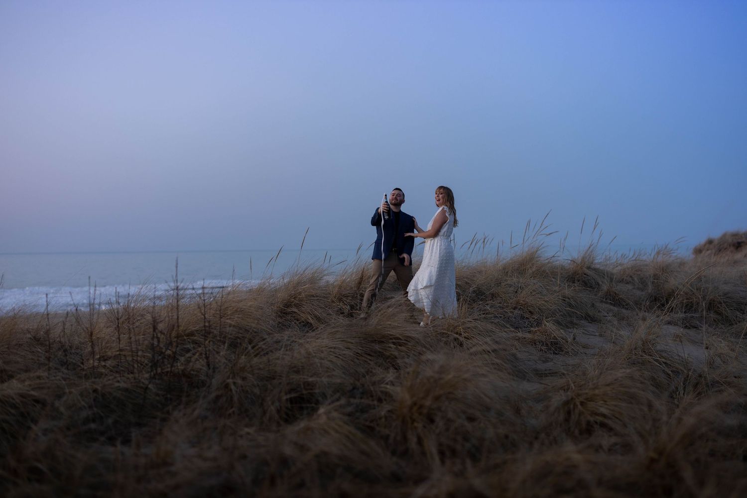 A panoramic sequence of people walking along a grassy hilltop trail against a misty blue sky at dusk.