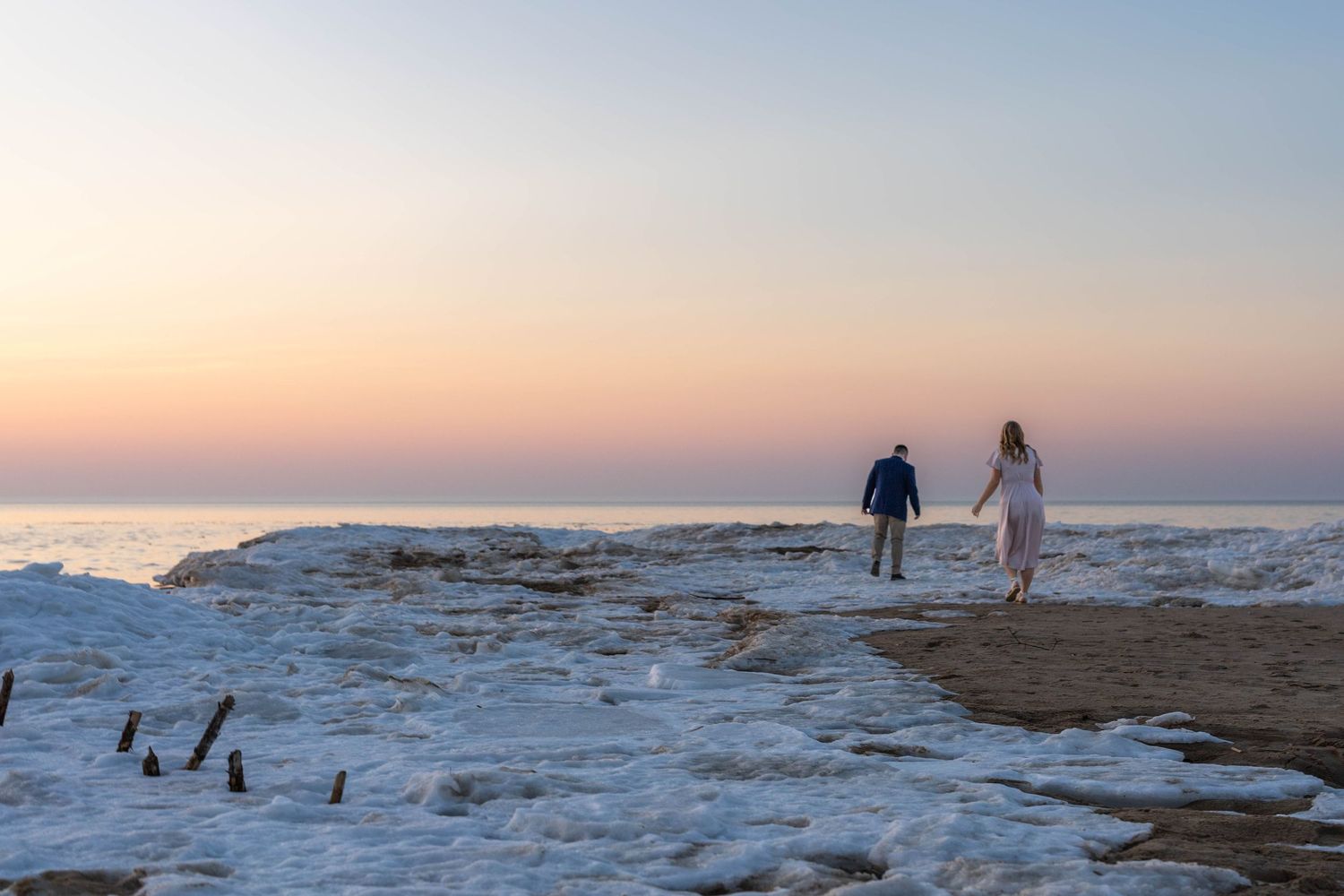 Group of people walking along a scenic snowy trail at sunset with beautiful winter landscape surroundings.