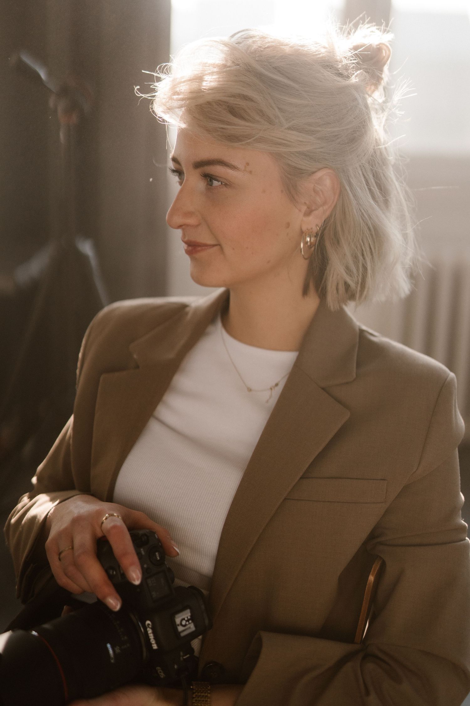 Sunlit portrait in brown blazer and white turtleneck with natural window lighting.