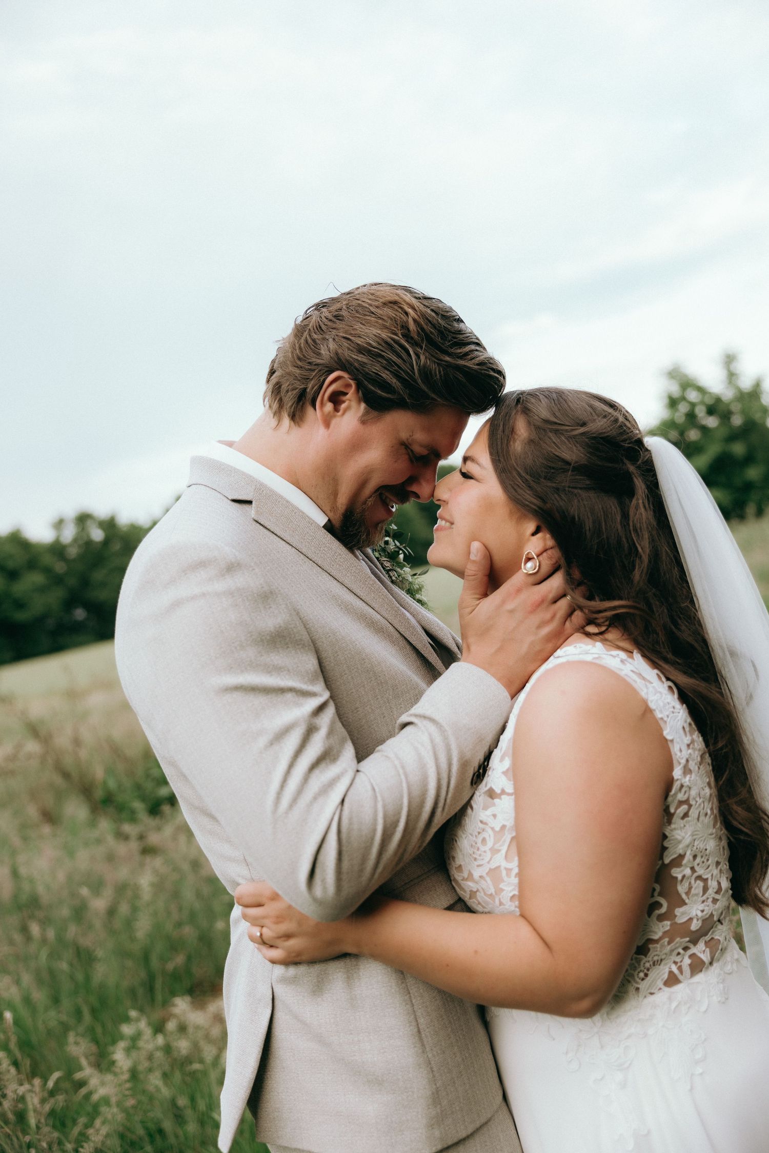 Romantic outdoor wedding photo sequence showing tender moments between newlyweds in a grassy field.
