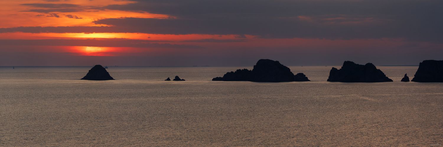 Le soleil rougeoyant s'enfonce dans l'Atlantique, teintant le ciel de pourpre derrière les silhouettes sombres des iconiques Tas de Pois.