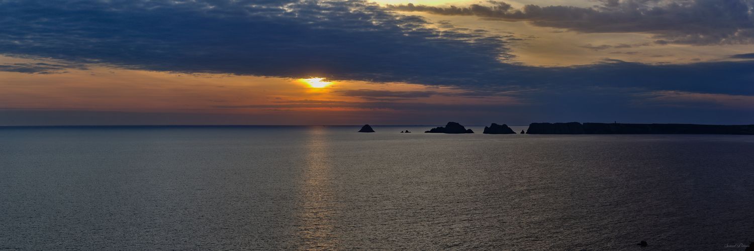 Un coucher de soleil flamboyant perce les nuages, illuminant l'océan et les silhouettes iconiques des Tas de Pois à Camaret-sur-Mer.