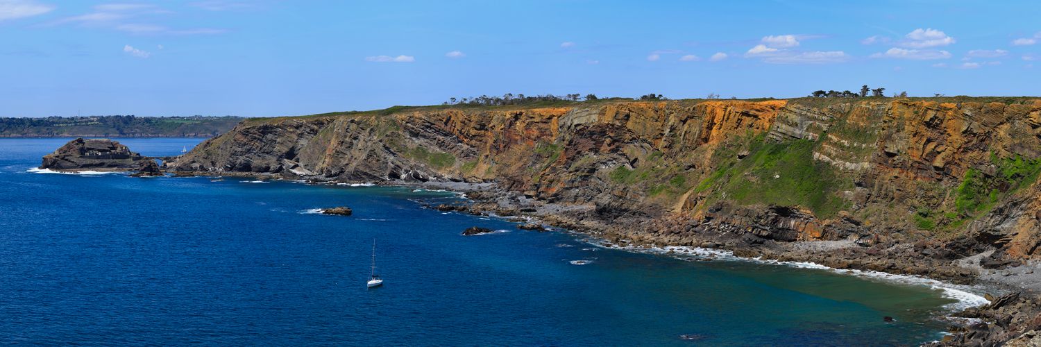 Fort des Capucins sur son îlot rocheux, relié par un pont de pierre. Falaises escarpées, mer d'Iroise limpide et voilier blanc au loin.