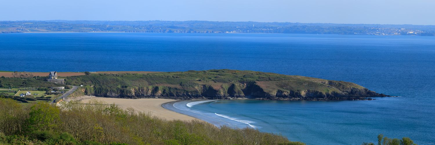Rivage sauvage à la Pointe du Bellec : l’écume turquoise caresse le sable fin tandis que les falaises plongent dans une mer d'azur infinie.