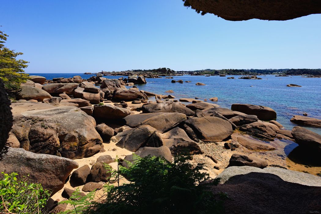Paysage littoral de la Côte de Granit Rose, entre rochers ocres sculptés, mer bleu azur et horizon lumineux. Une évasion minérale.