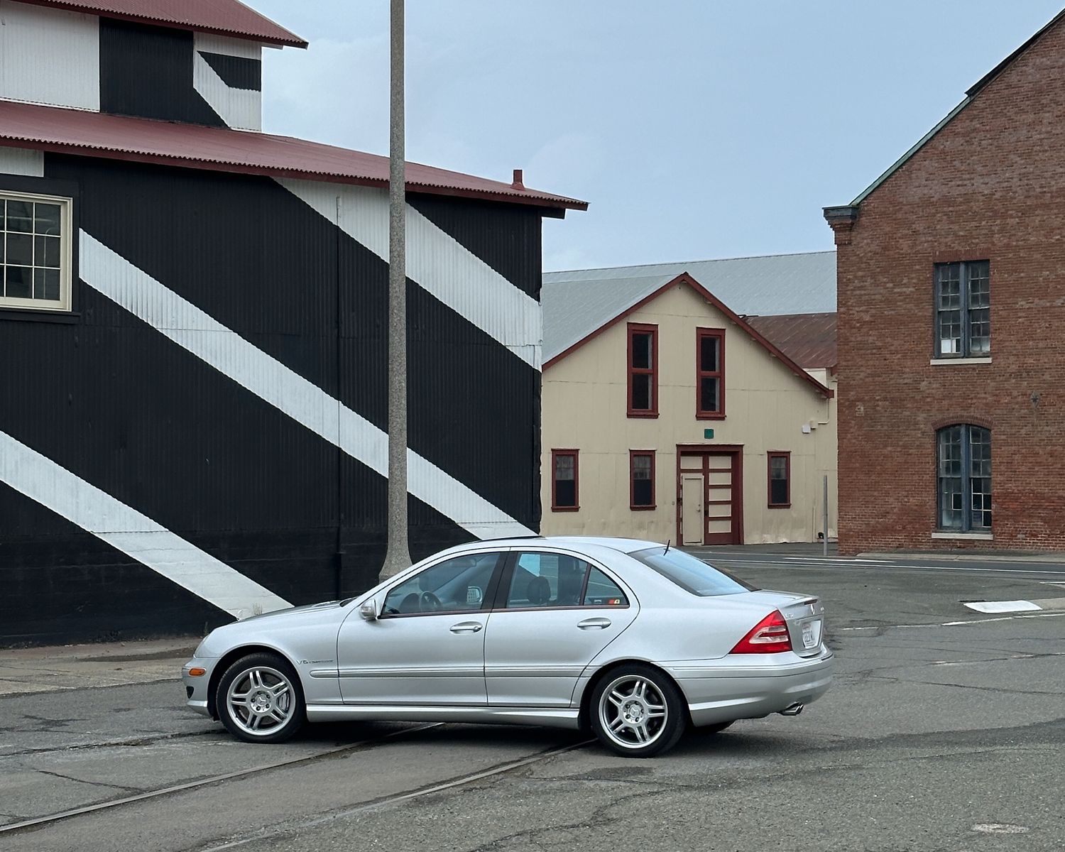 A photo of the C32 AMG sedan from side, taken in the fall at Mare Island, California among classic warehouse buildings.