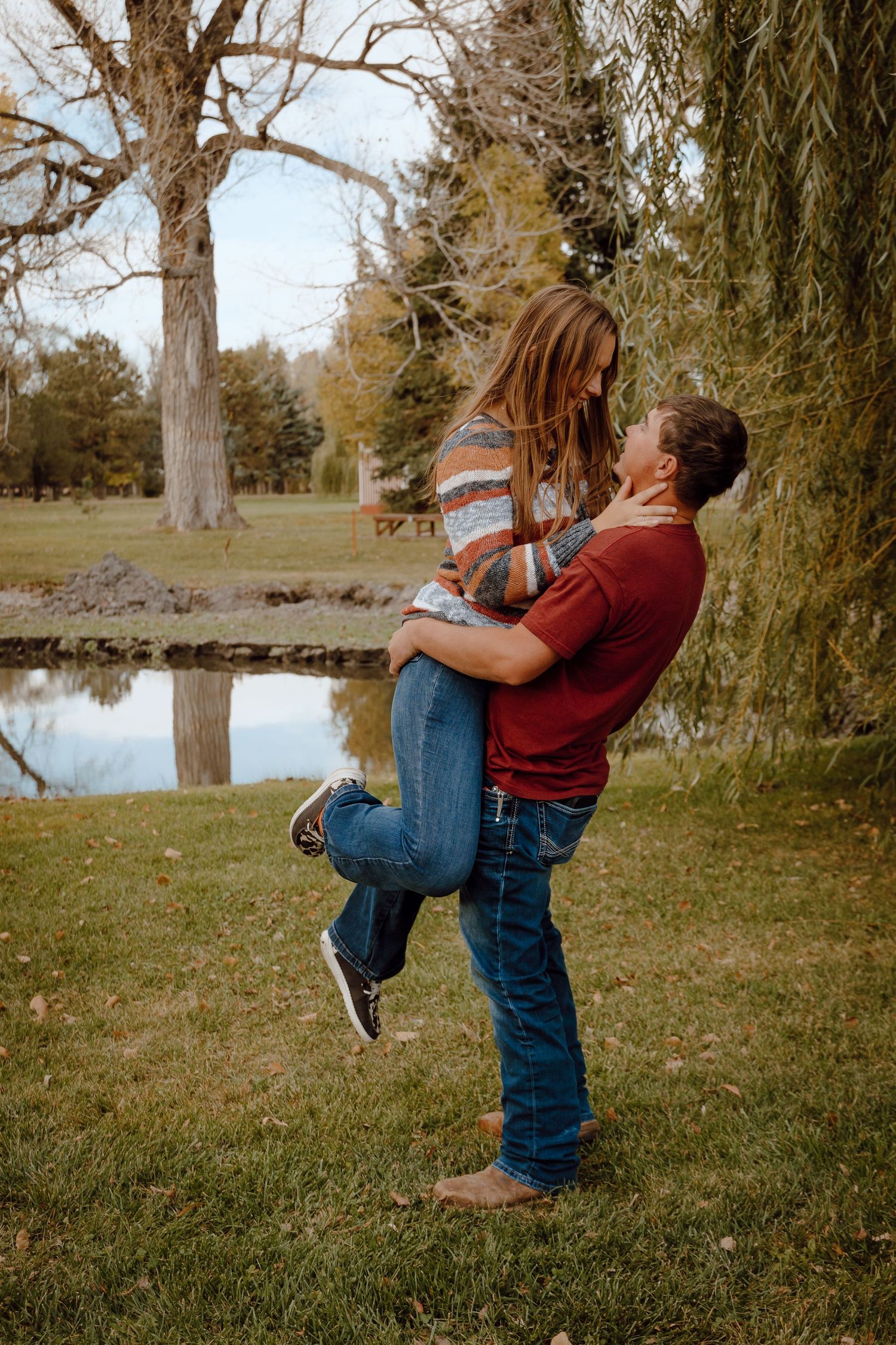 A North Platte, Nebraska lifestyle couple session couple embracing under a willow tree in warm golden light.