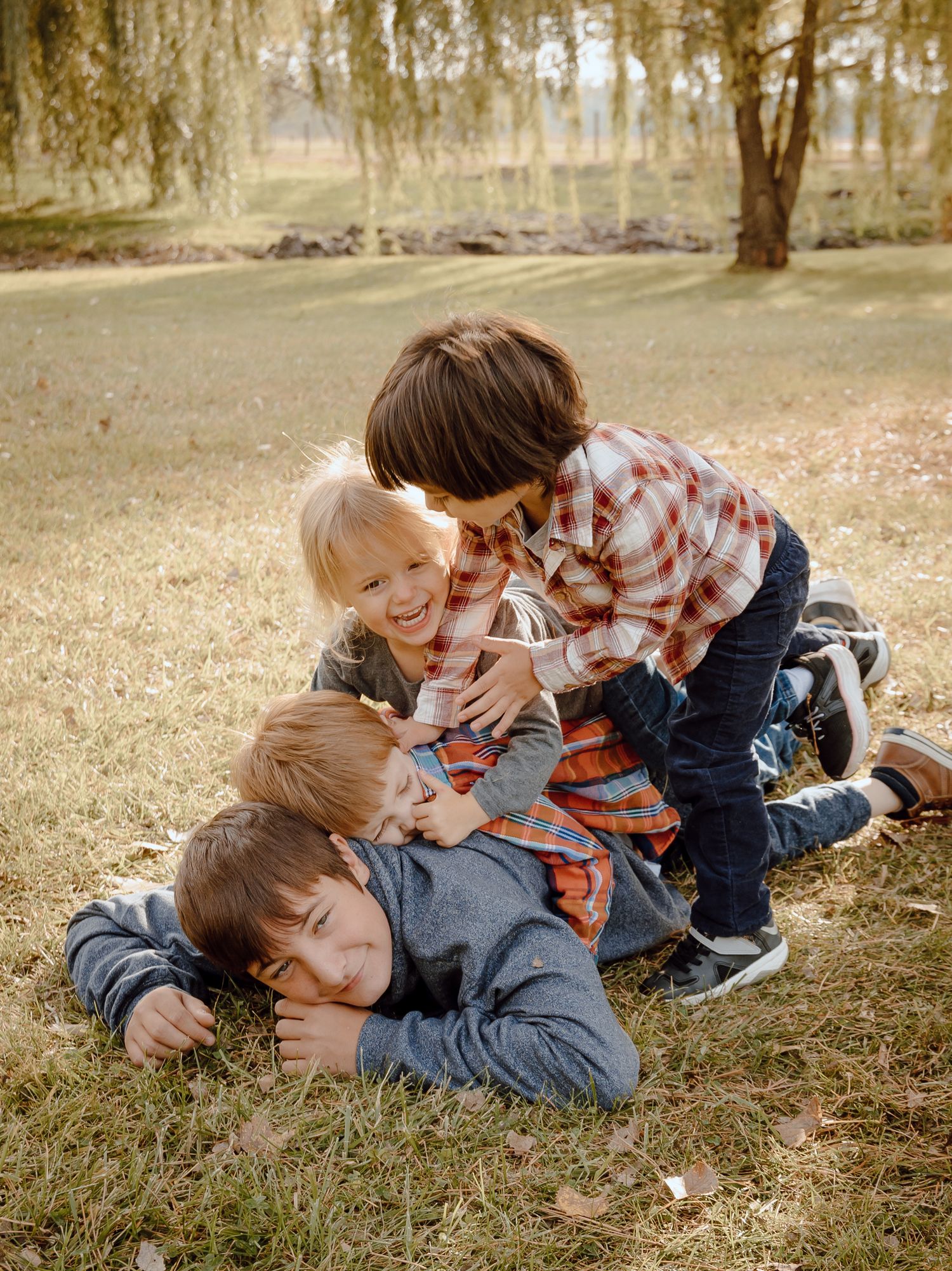 A North Platte, Nebraska lifestyle family session cousins playing and rolling together on grass in a natural outdoor setting.