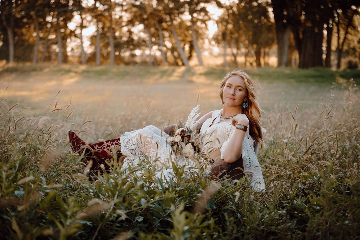 A North Platte, Nebraska lifestyle session woman in a white dress sitting in a golden field during sunset.