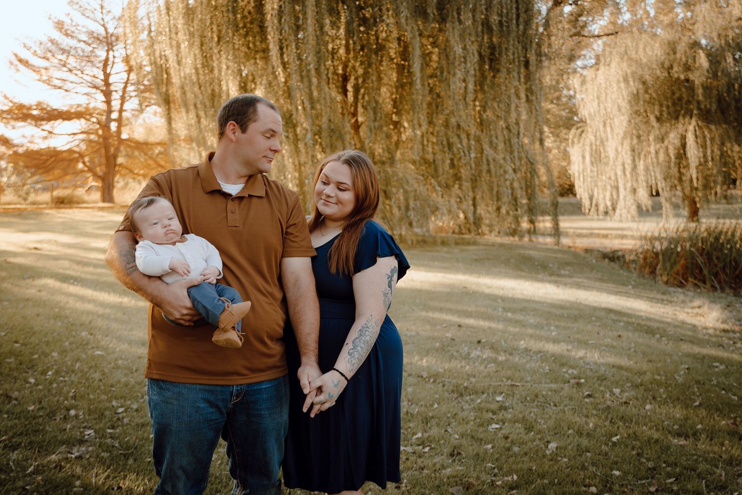 A North Platte, Nebraska lifestyle family session family walks together on a tree-lined path during golden hour.