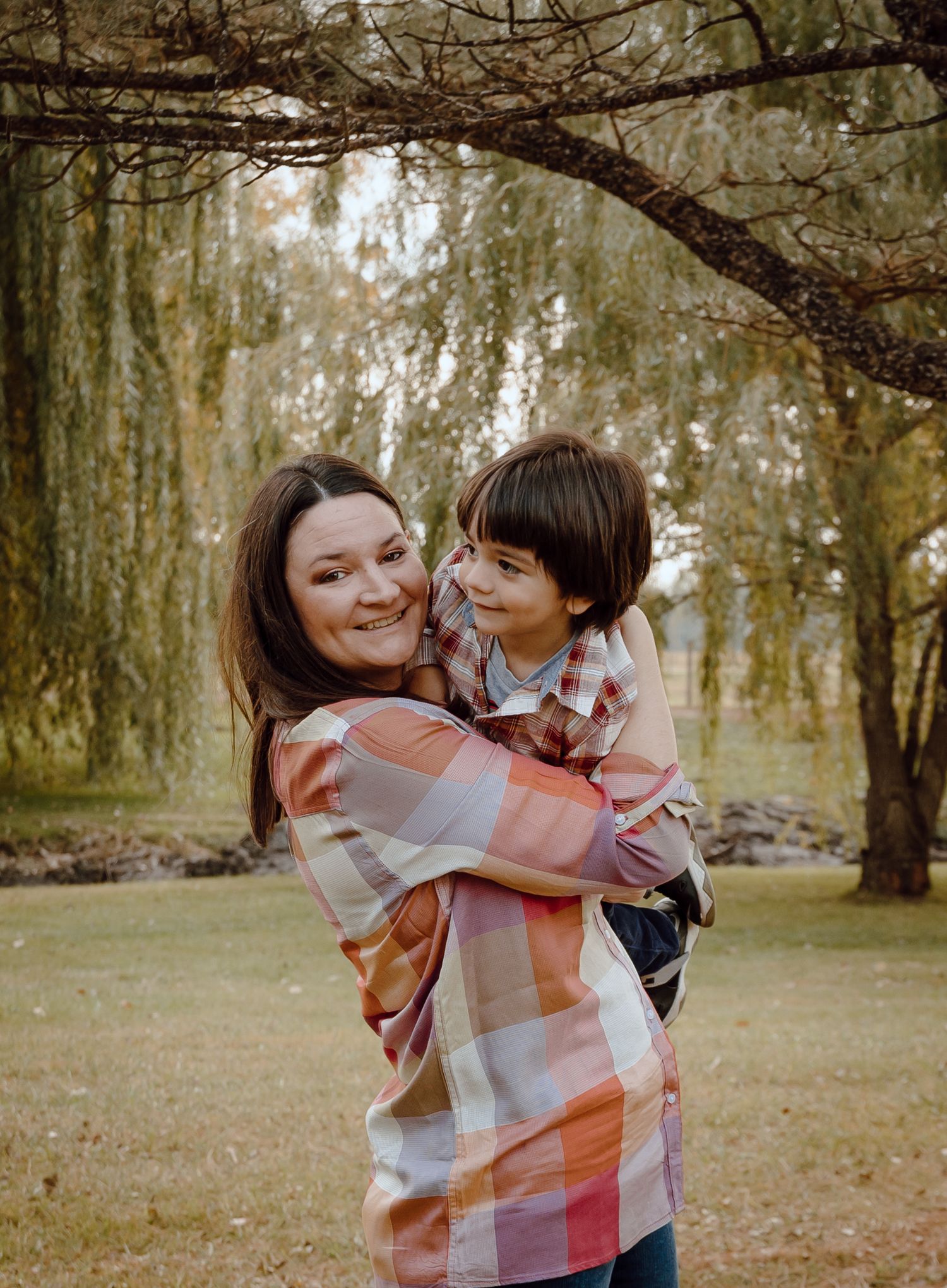 A North Platte, Nebraska lifestyle family session mom and her son share joyful moments together in a sunlit wooded area.