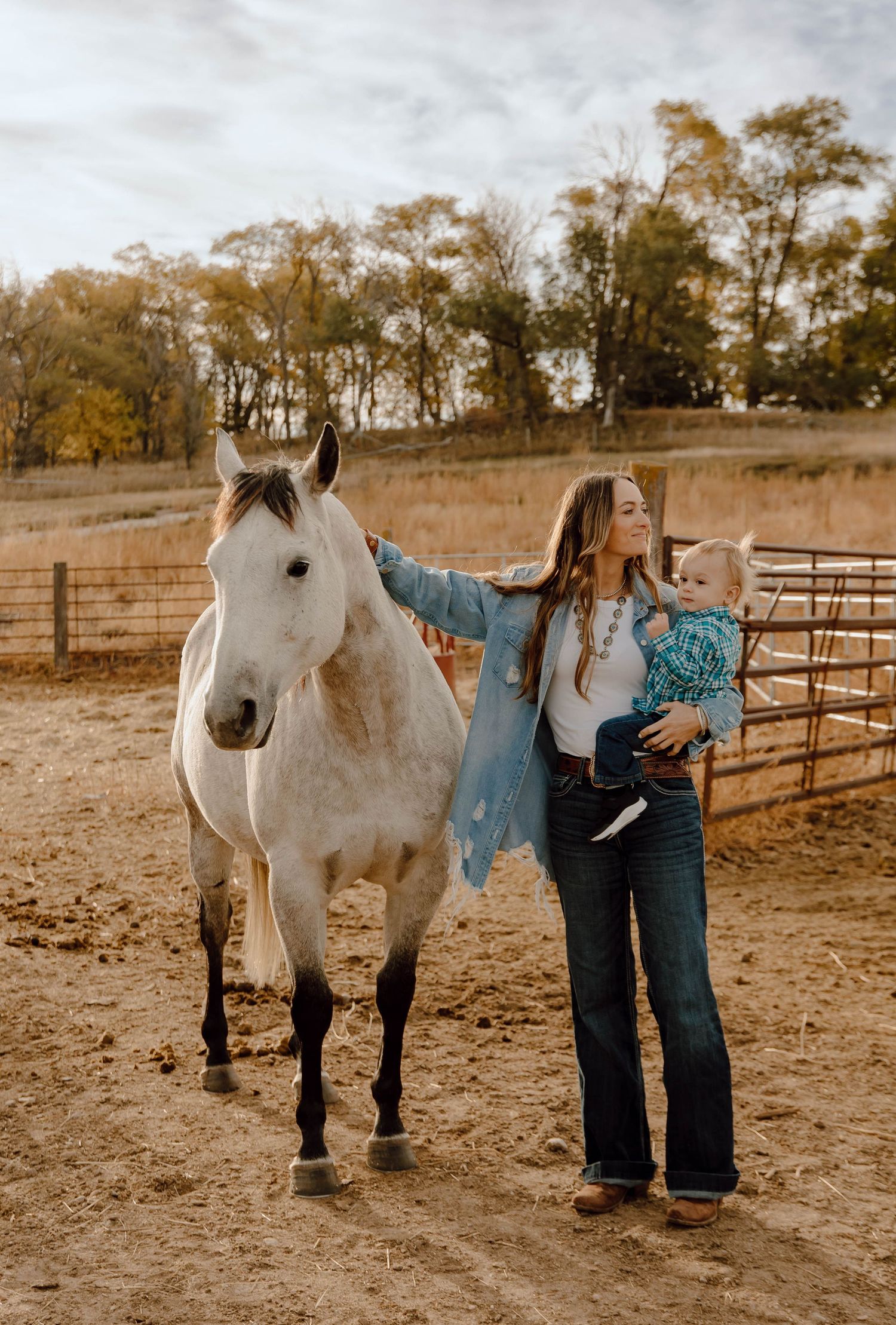 Sutherland, Nebraska lifestyle family session mom and her baby in a fenced corral petting a gray horse.