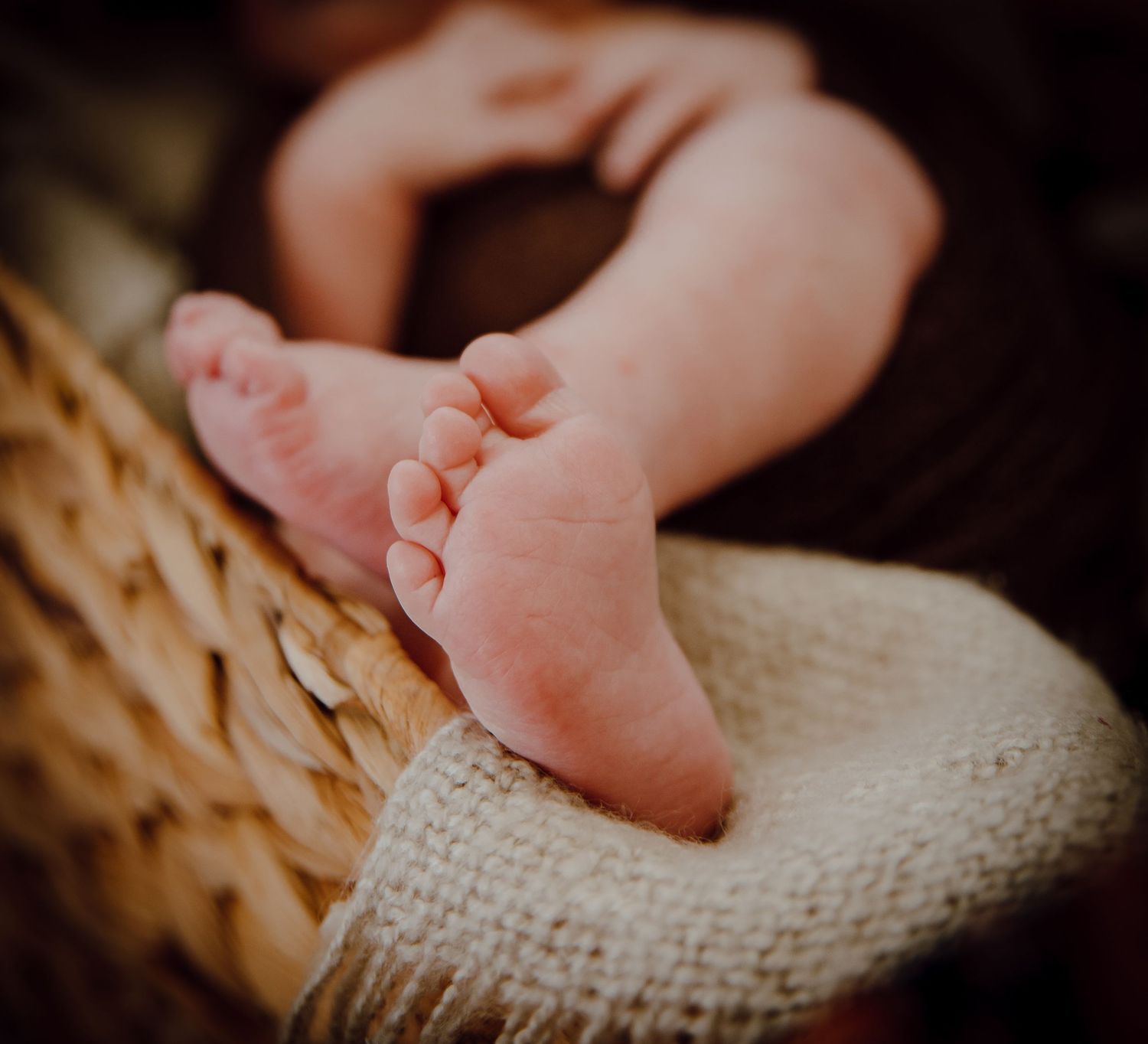 A North Platte, Nebraska lifestyle newborn session tiny baby feet resting on a soft knitted cream-colored blanket in warm lighting.