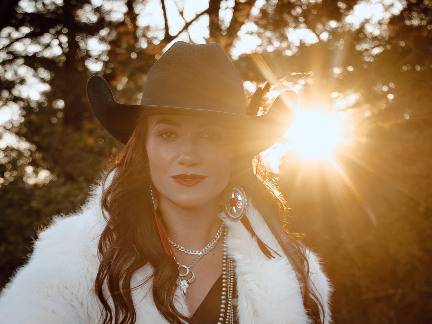 A North Platte, Nebraska lifestyle session woman in a cowboy hat stands against golden sunset.