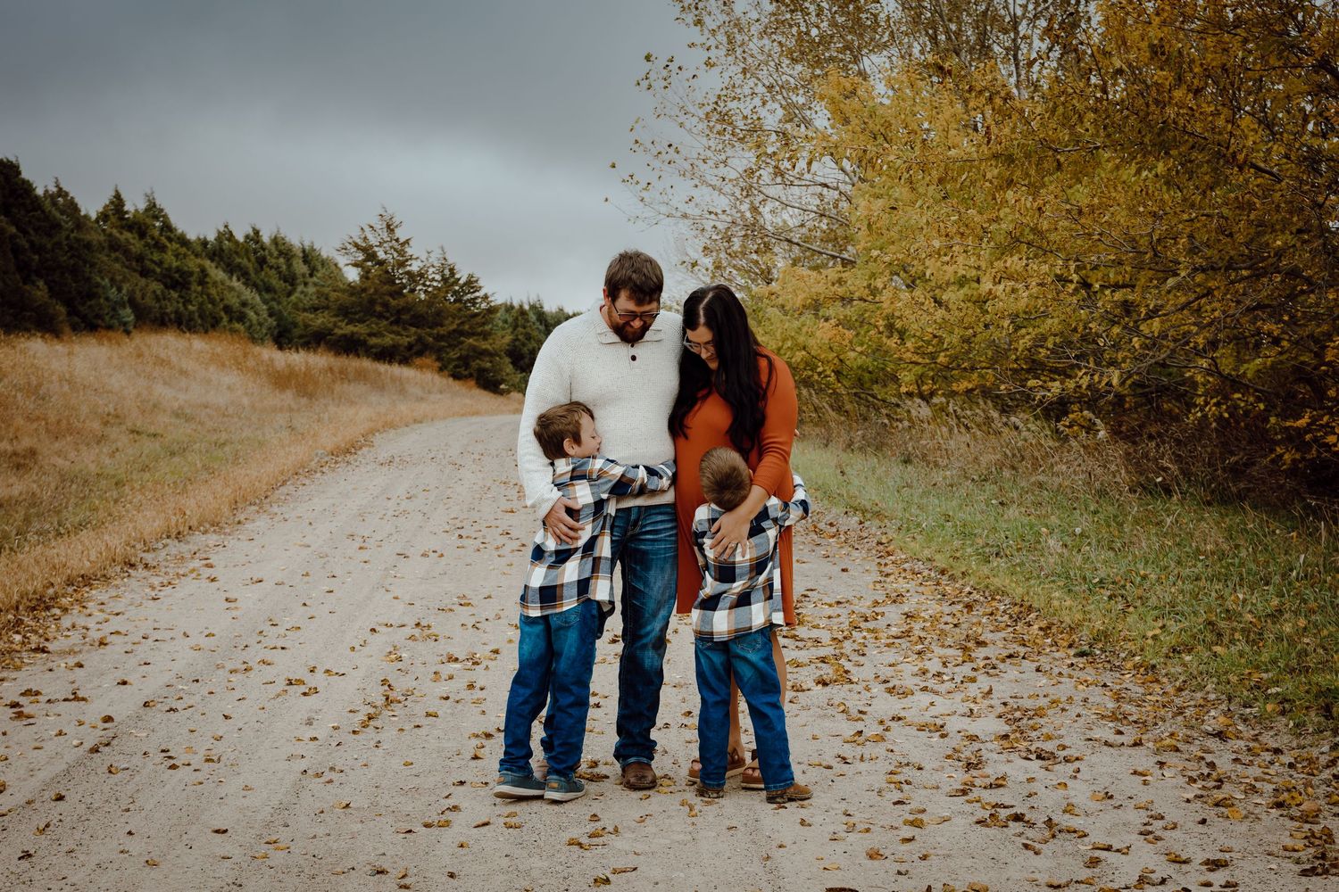 A Sutherland, Nebraska lifestyle family session family walks together on a winding dirt path through autumn foliage.
