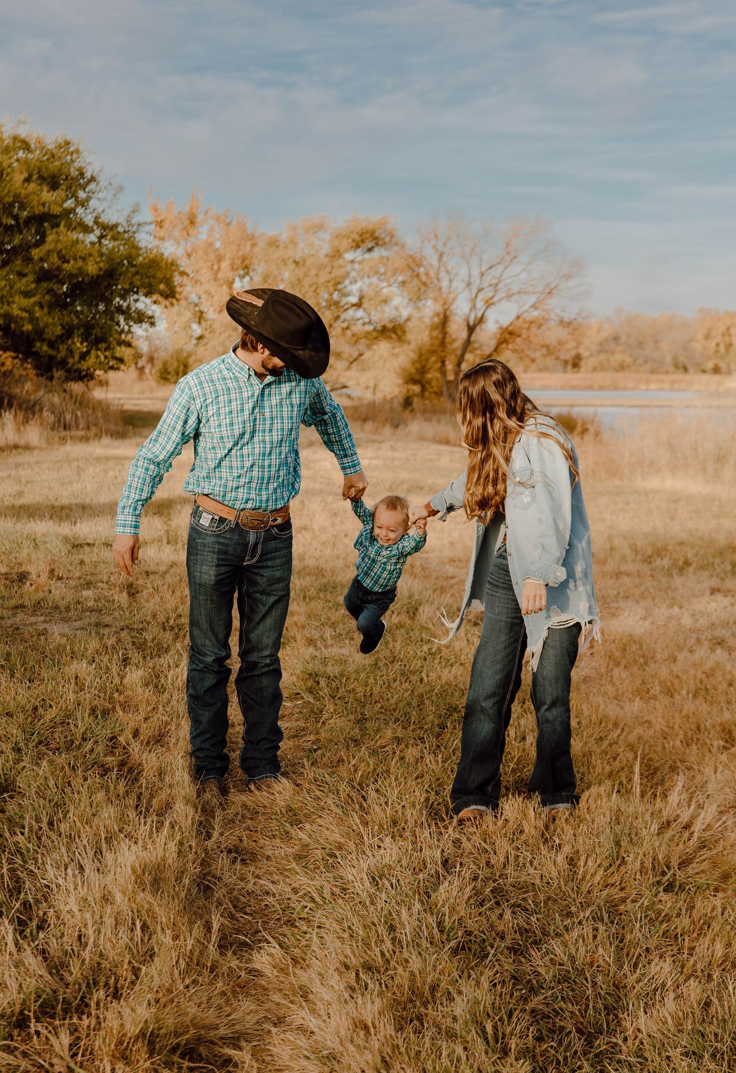 A Sutherland, Nebraska lifestyle family session family walks through a golden autumn field at sunrise.