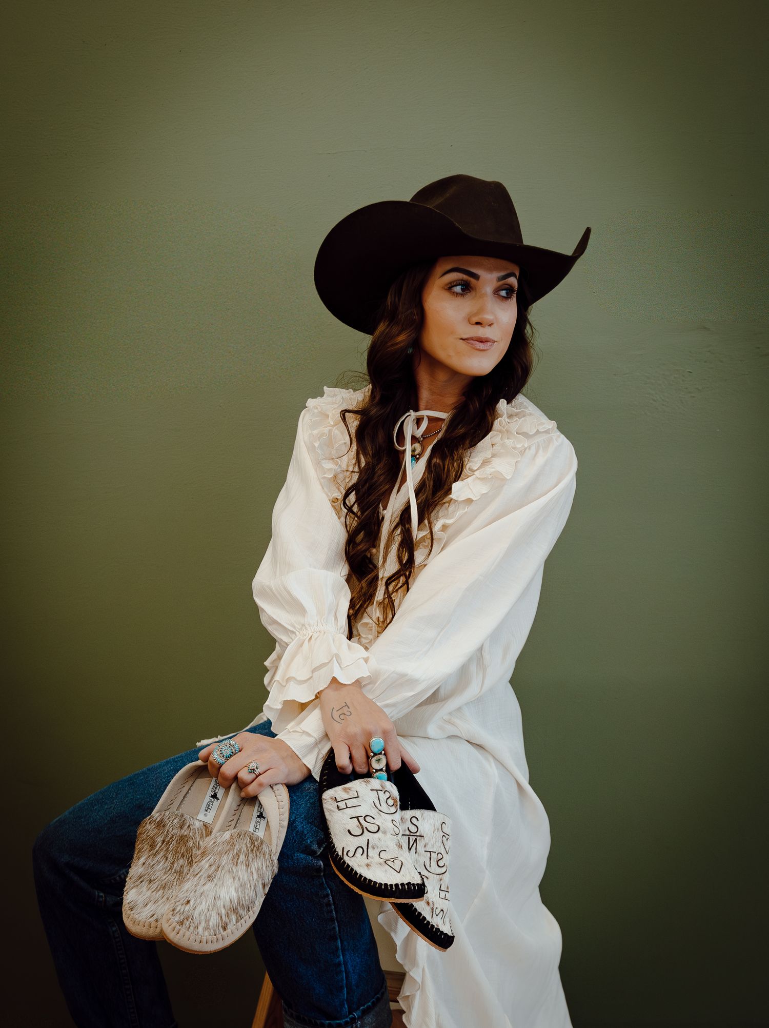 A North Platte, Nebraska lifestyle brand session woman in western attire and cowboy hat poses against a green background.