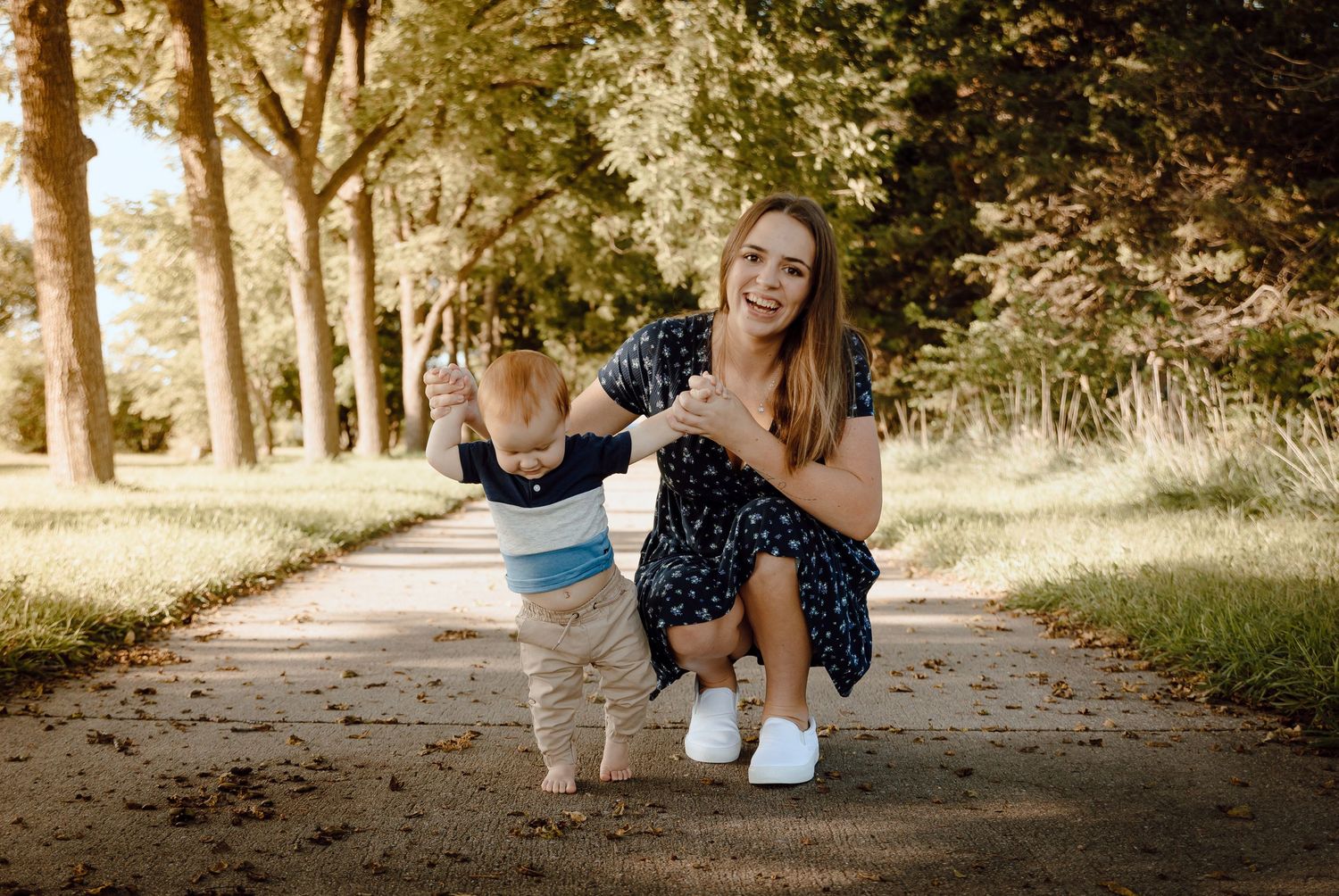 A North Platte, Nebraska lifestyle family session mom and her baby together on a path surrounded by trees in an outdoor setting.