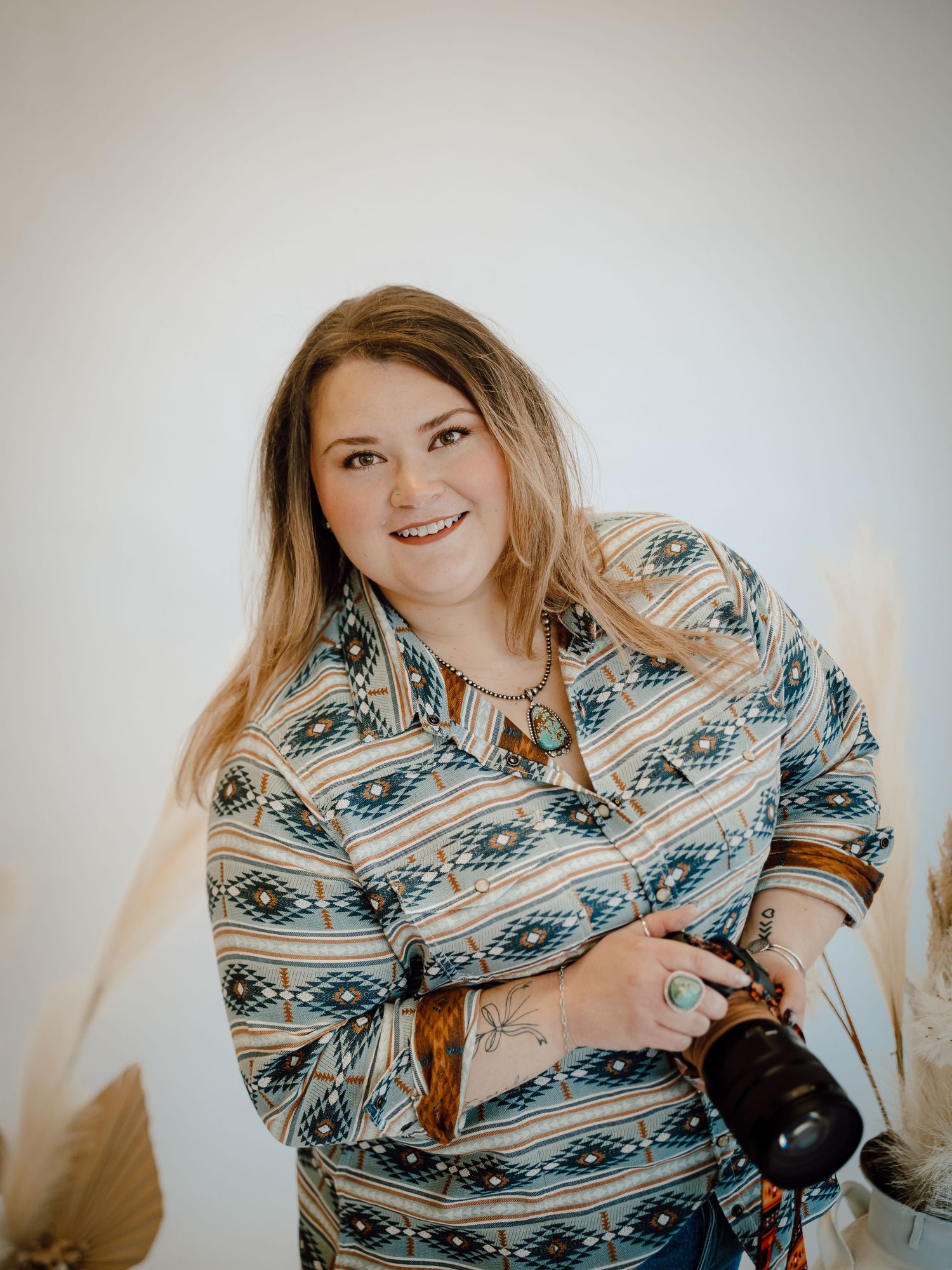 A North Platte, Nebraska lifestyle photographer in a patterned blue and white button-up shirt poses.