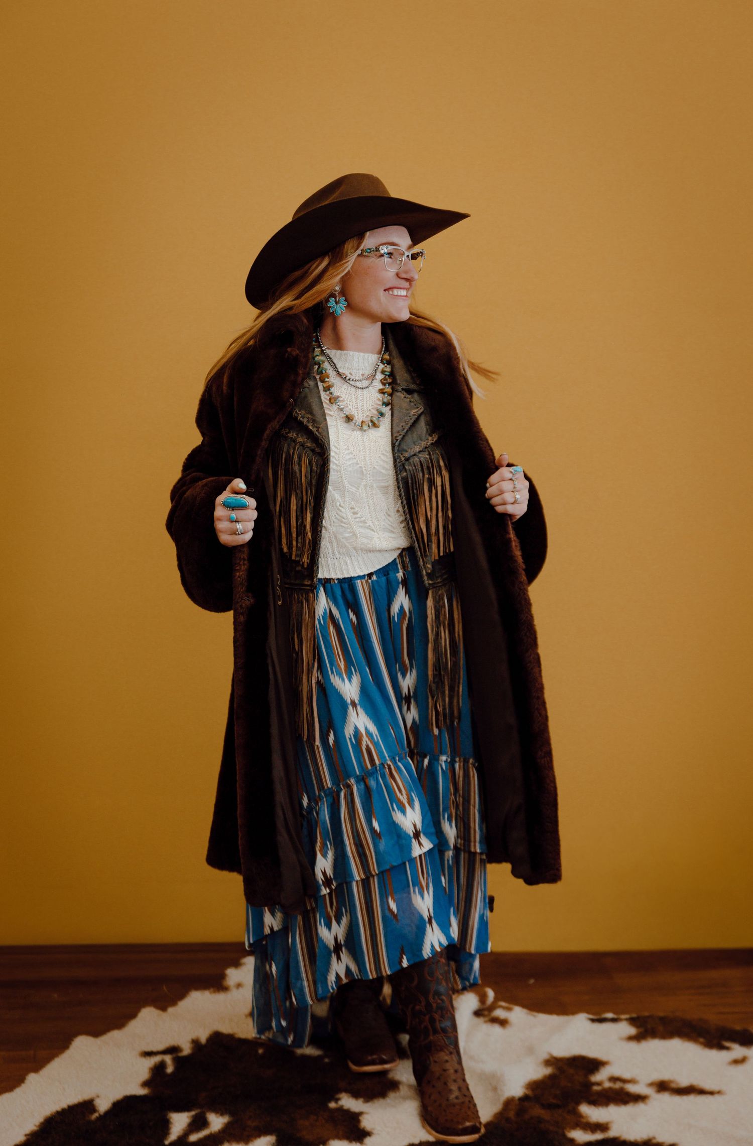 A North Platte, Nebraska lifestyle brand session woman in a cowboy hat poses playfully against a yellow backdrop.