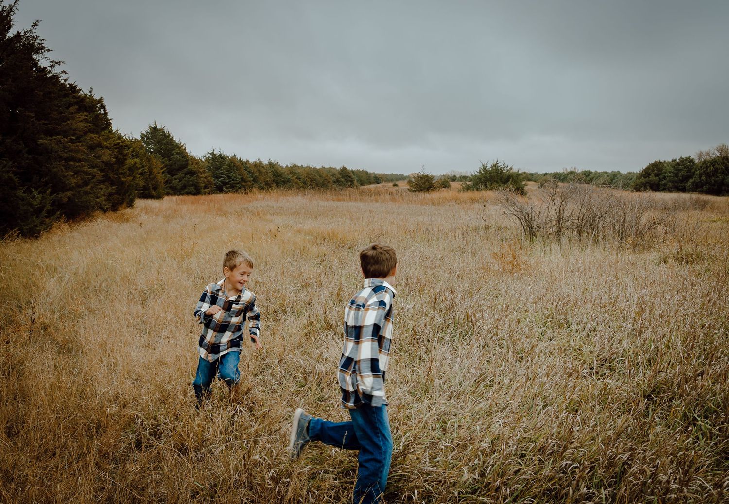 A Sutherland, Nebraska lifestyle family session children play tag in a golden autumn field.