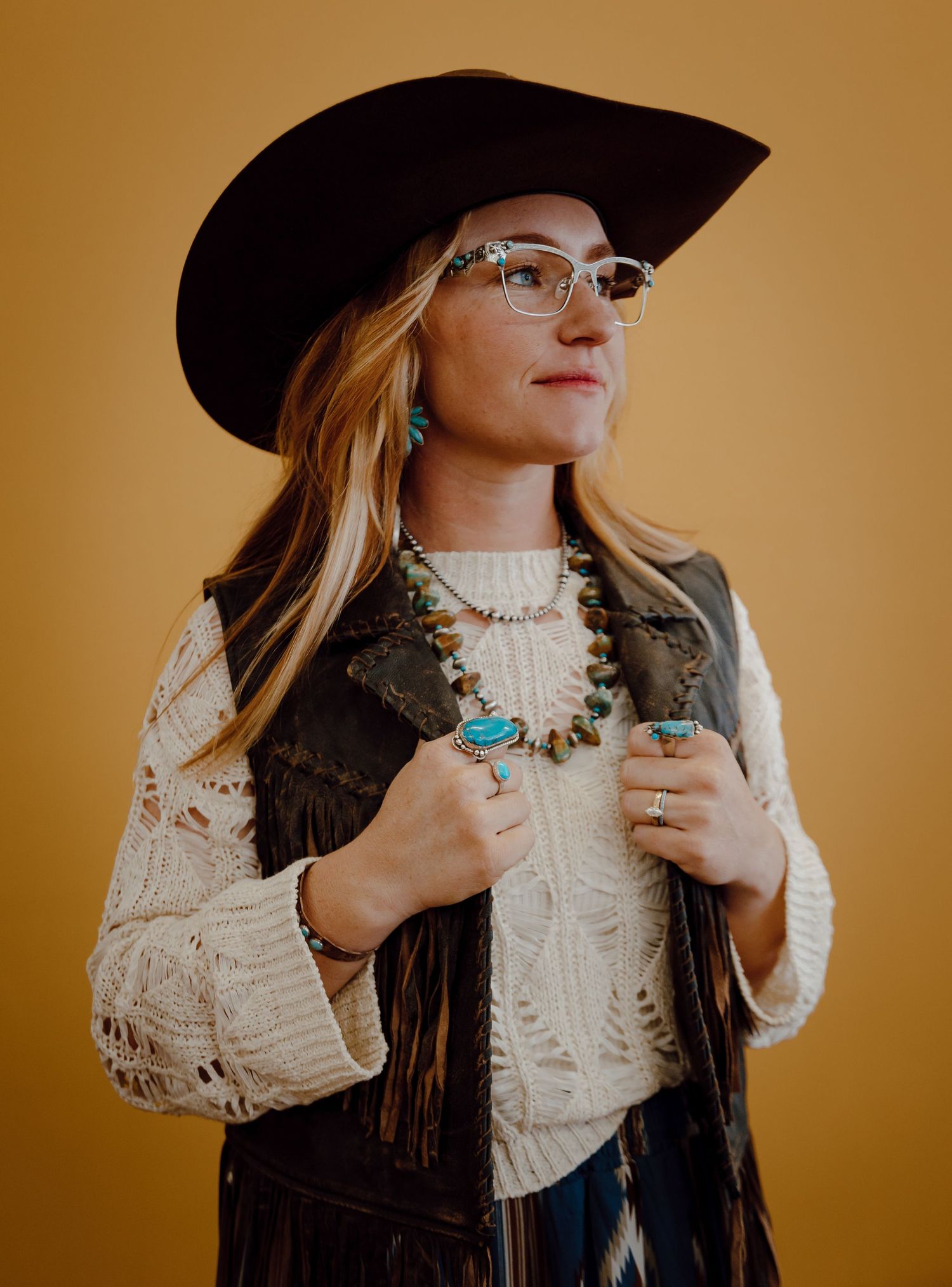 A North Platte, Nebraska lifestyle brand session woman wears western attire while modeling turquoise jewelry.