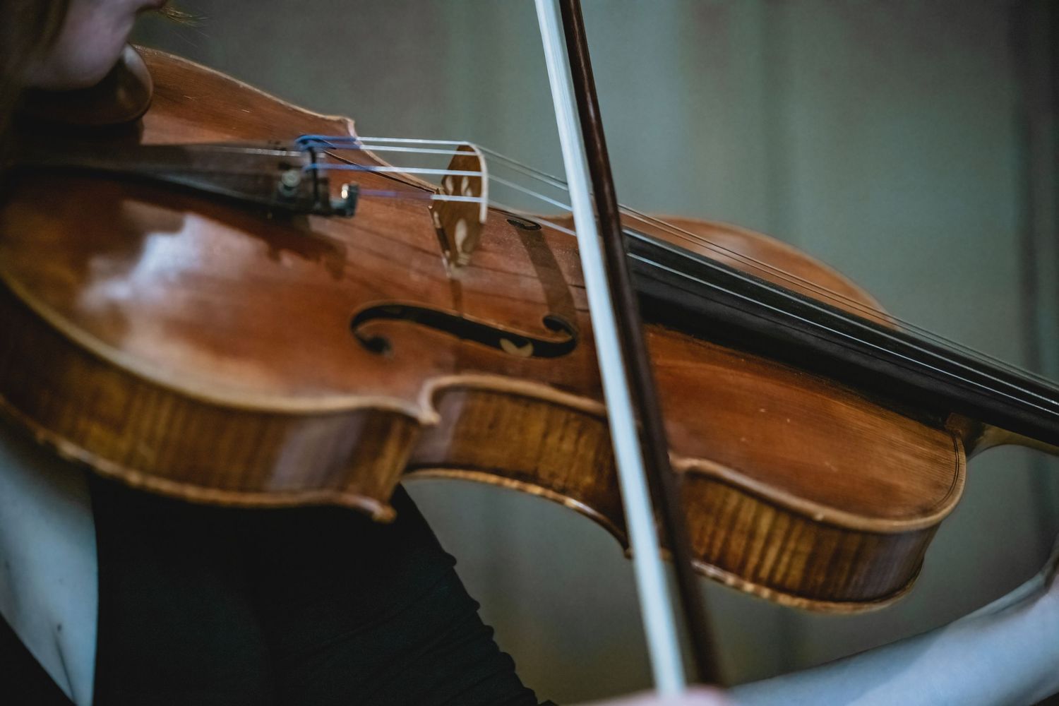 Close-up of a violinist playing a wooden violin with bow during a wedding ceremony.