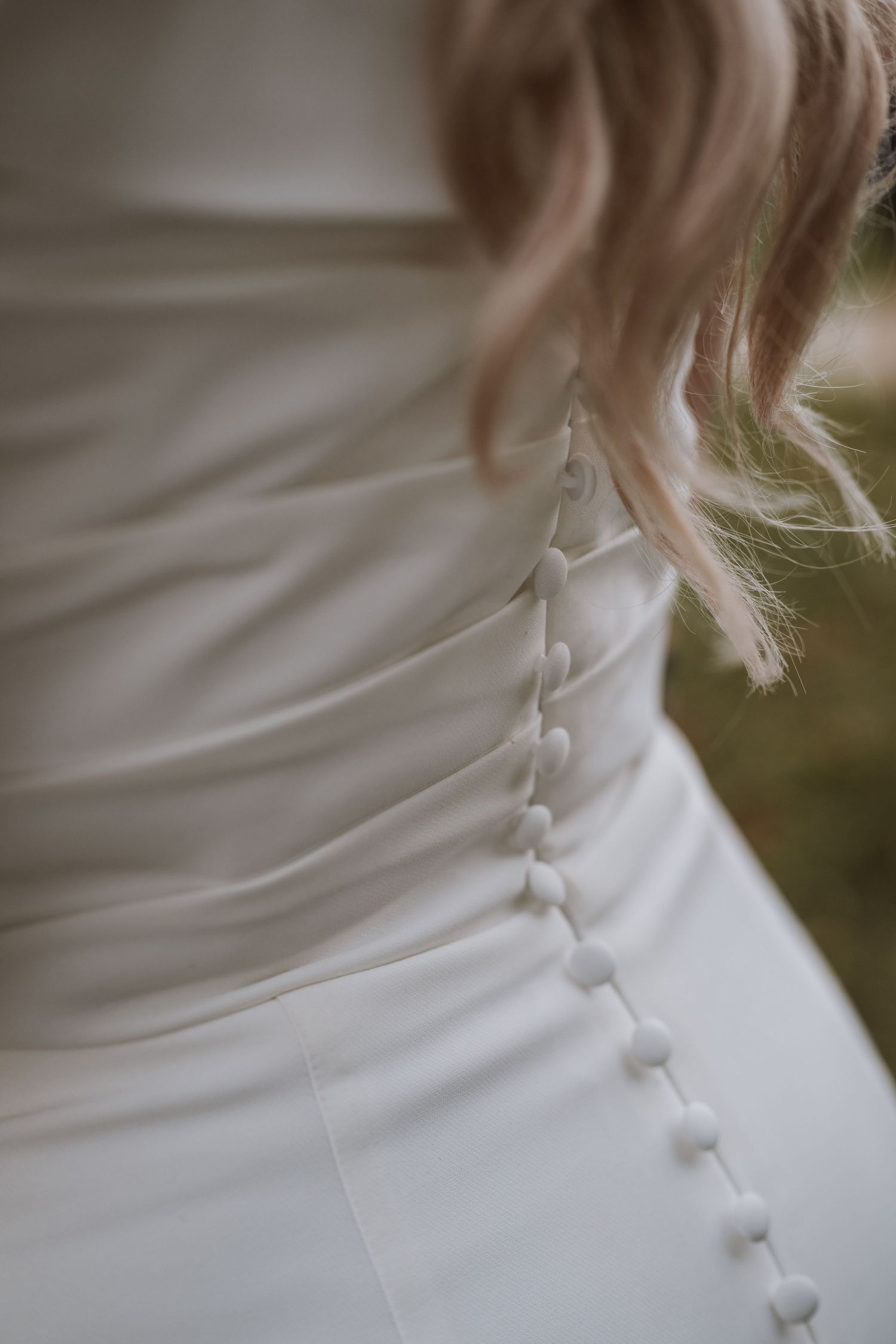 Close-up detail of elegant white wedding dress with delicate button back closure.