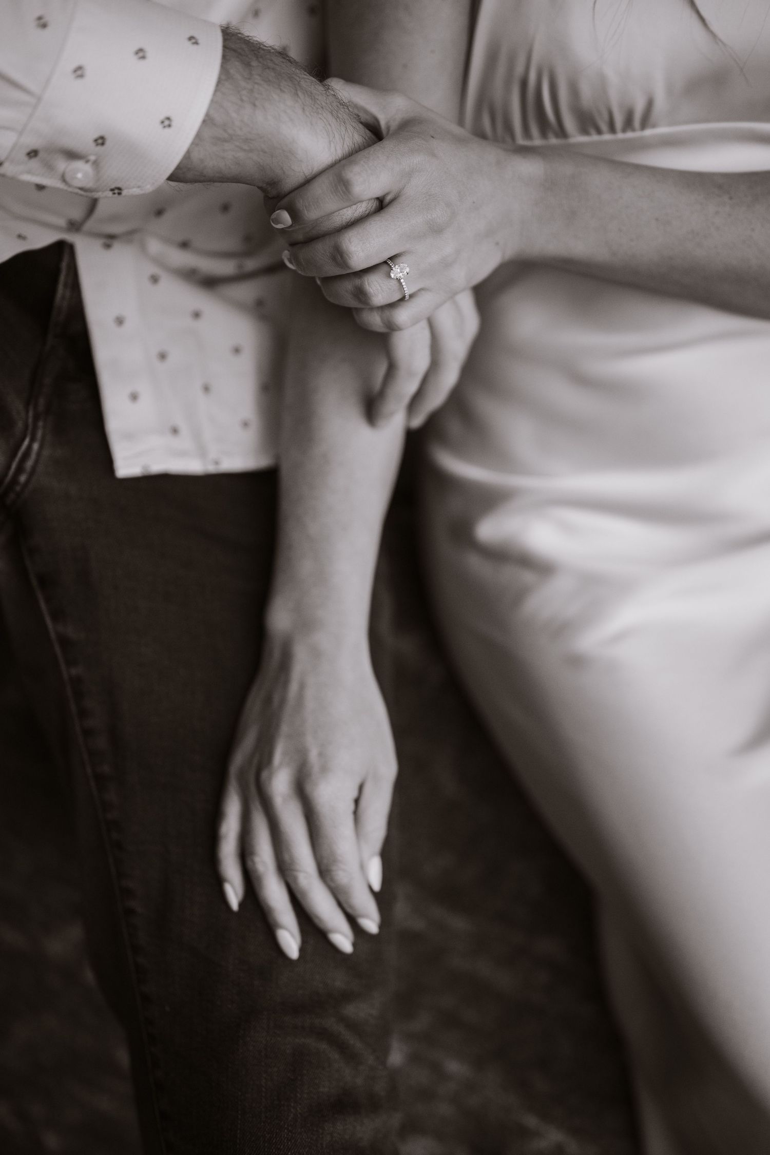 Black and white close-up of a couple holding hands, bride wearing a diamond engagement ring.