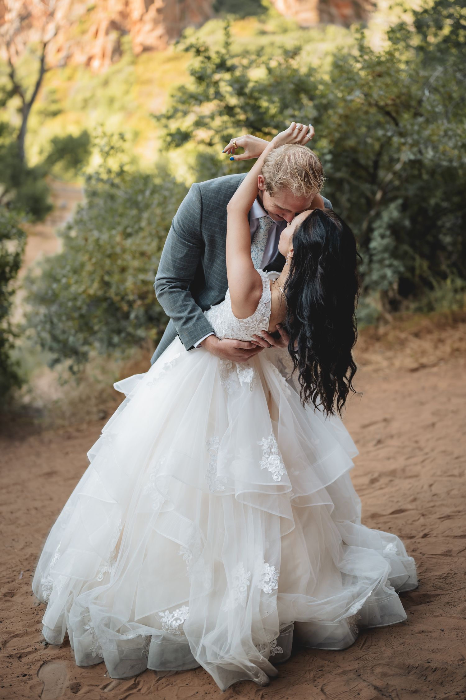 Bride and groom share a romantic dip kiss surrounded by desert landscape at Zion.