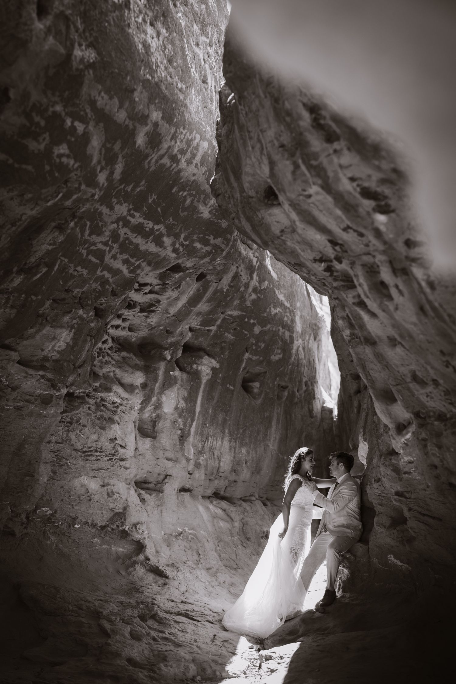 Black and white photo of bride and groom sharing intimate moment in dramatic rock canyon.