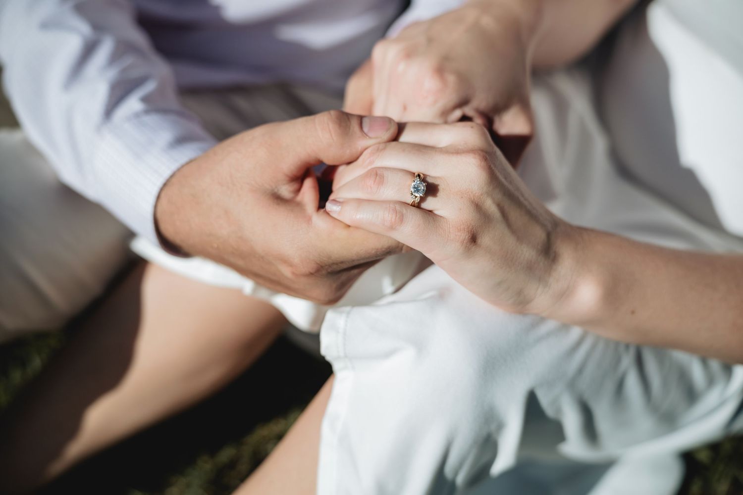 Close-up of couple holding hands with a diamond engagement ring, symbolizing love and commitment.