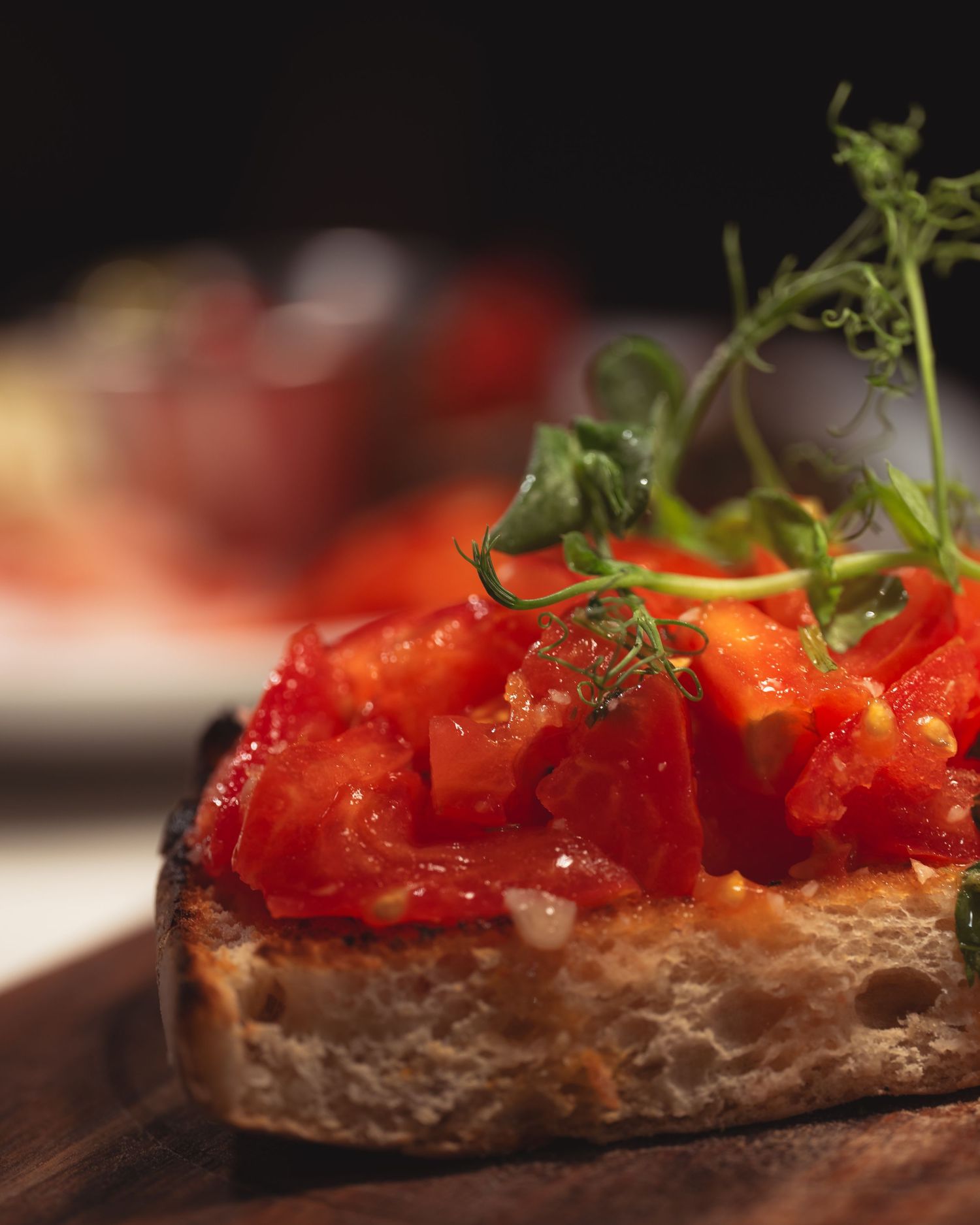 Close-up of bruschetta topped with bright red tomatoes and fresh herbs from Little Tuscany.