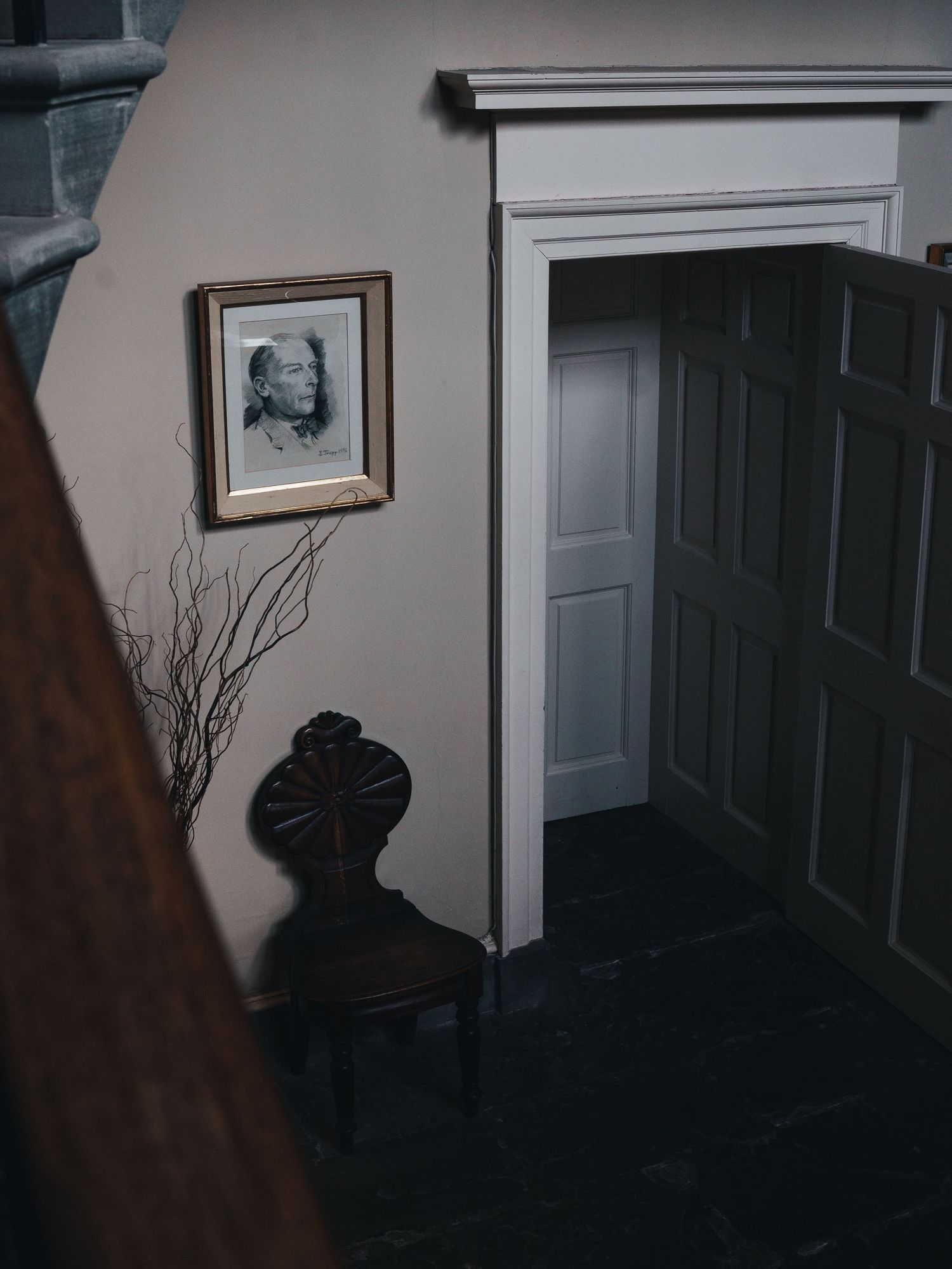 A vintage chair and framed portrait create an atmospheric corner in a historic interior. Wedderburn Castle.