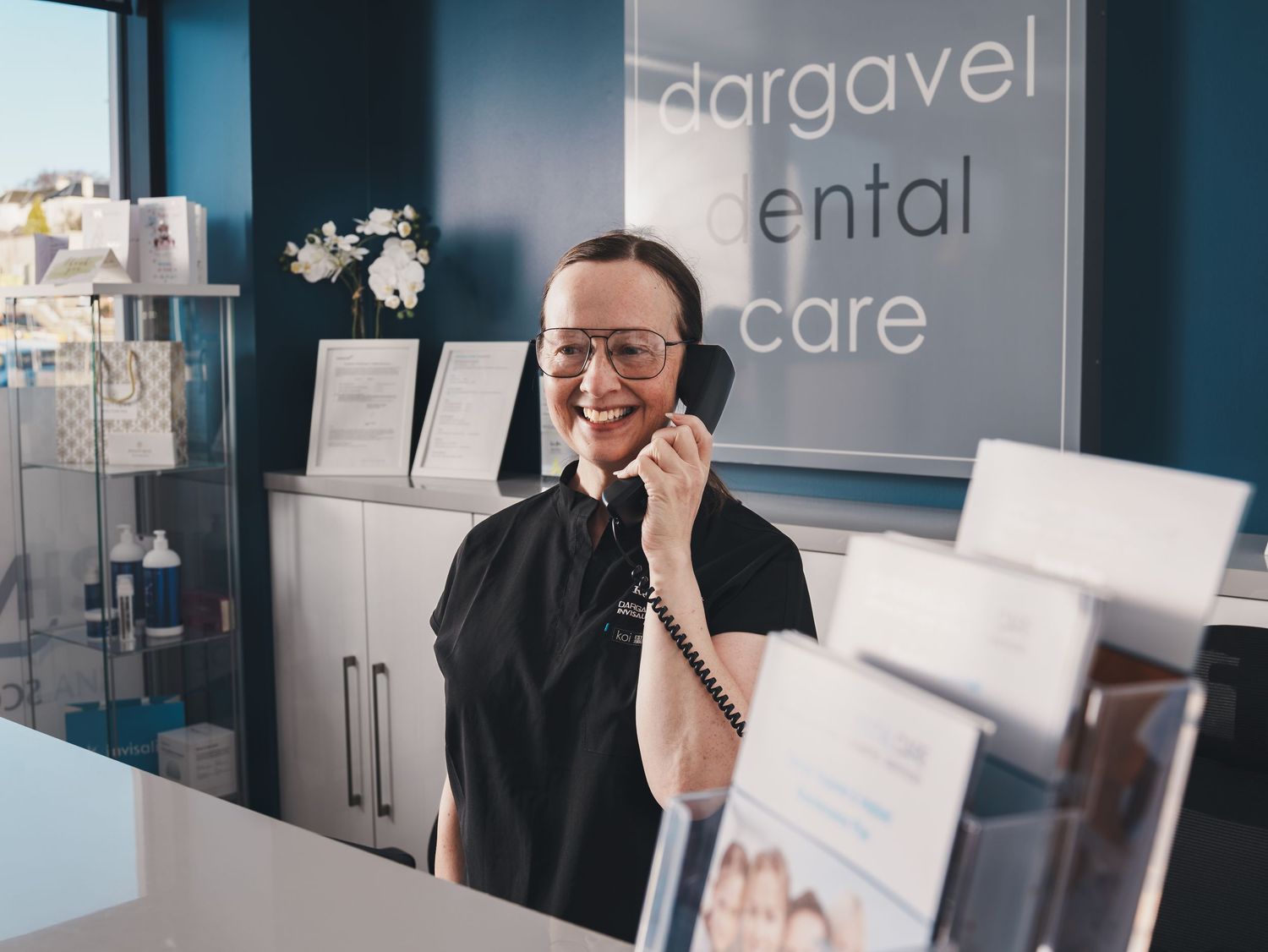 Modern dental office reception area with blue walls and branded signage. Dargavel Dental Care.