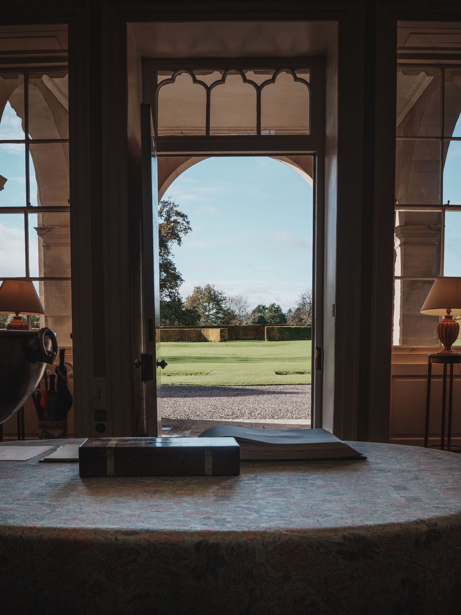 An elegant arched doorway frames a scenic view of manicured grounds and blue sky. Wedderburn Castle.