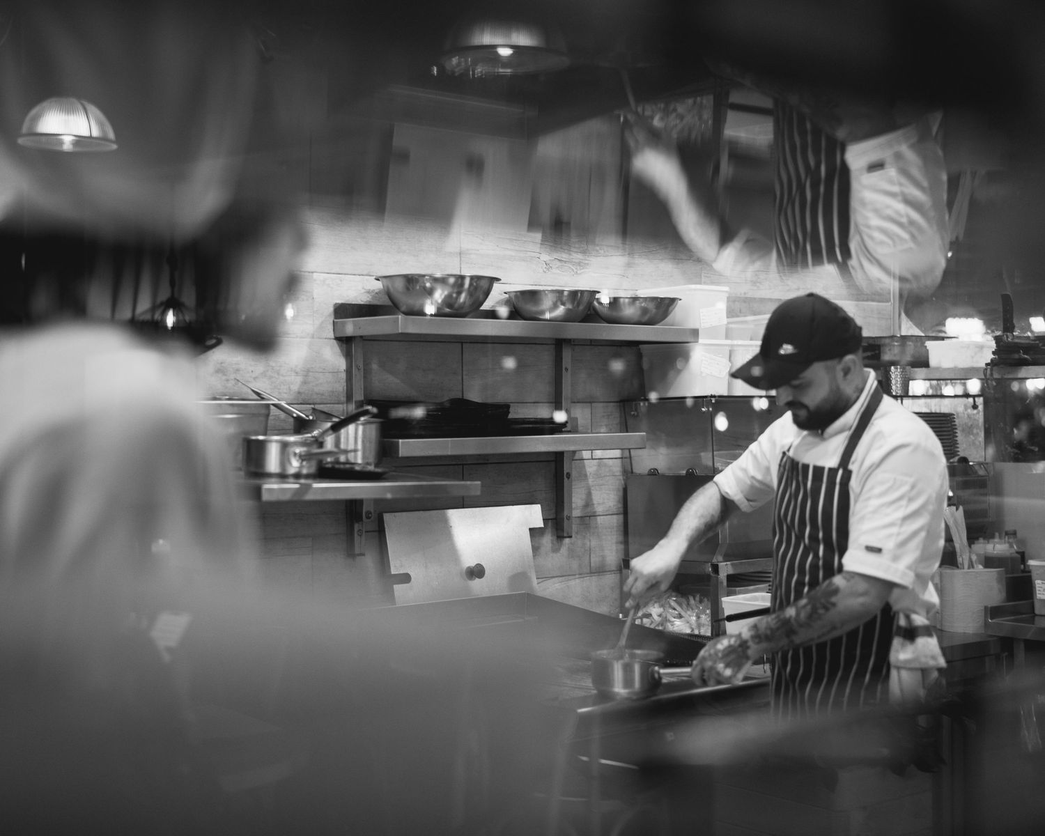 Black and white photo of a busy restaurant kitchen with staff preparing meals. Little Tuscany, Glasgow.