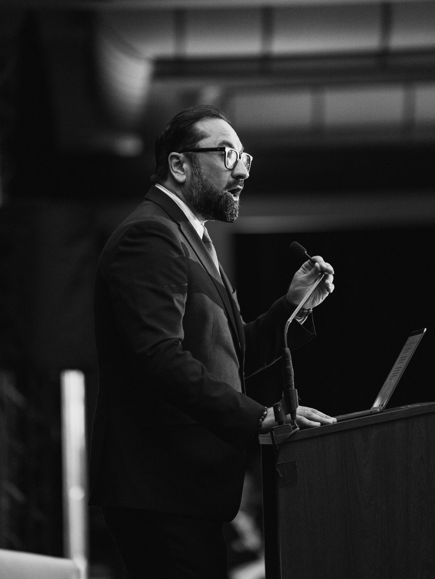 Black and white photo of a speaker at a podium during a presentation.