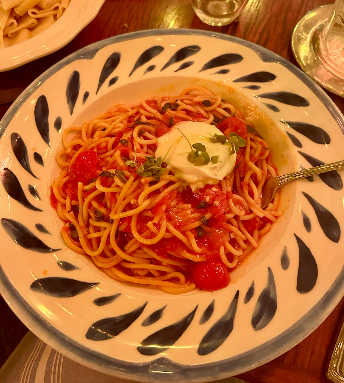 Plate of pasta with tomato sauce and fresh basil on patterned dish